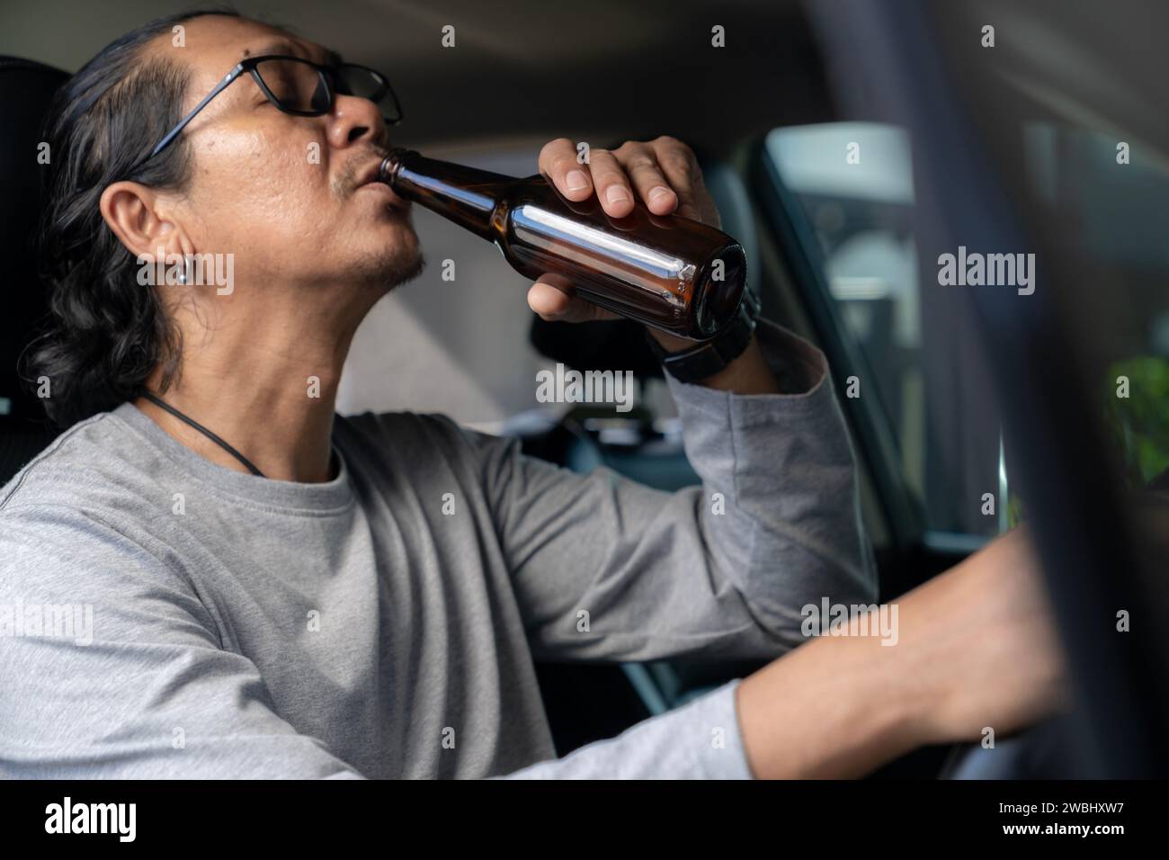 Ein Mann trinkt Bier während der Fahrt Stockfoto