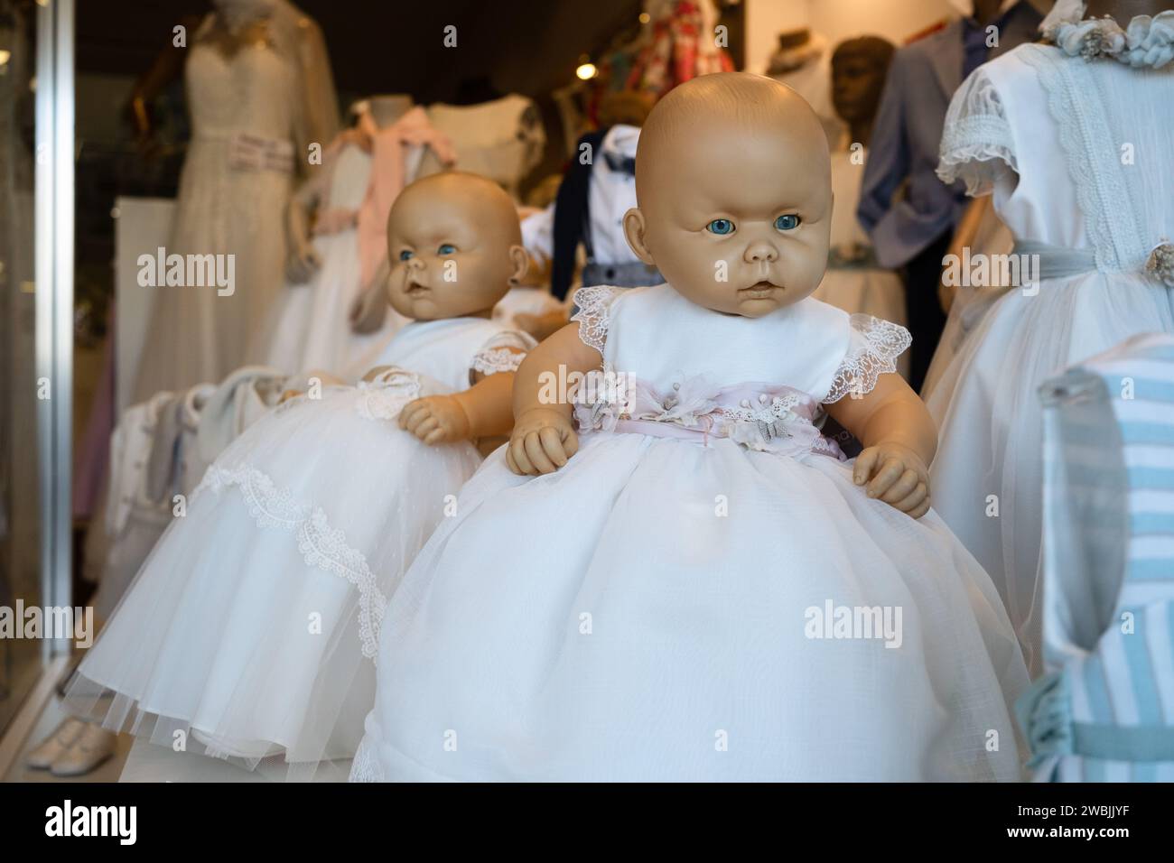 Ein bisschen gruselige blauäugige Puppen in weißen Kleidern im Schaufenster in Porto, Portugal Stockfoto
