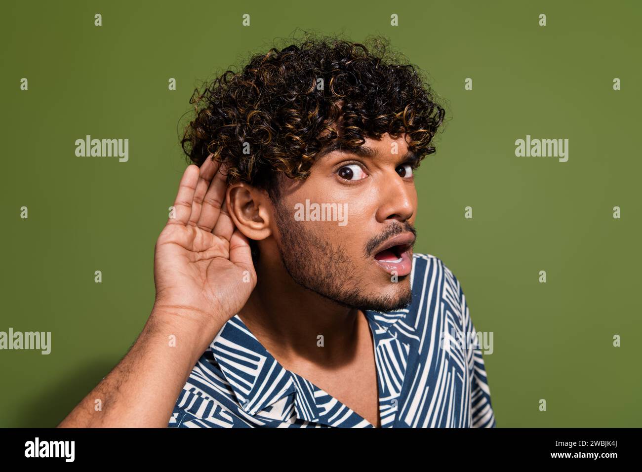 Nahaufnahme eines lustigen, ungeschraften indianers Hörensagen, der geheime Informationen über den Krieg mit pakistan hört, isoliert auf khakifarbenem Hintergrund Stockfoto