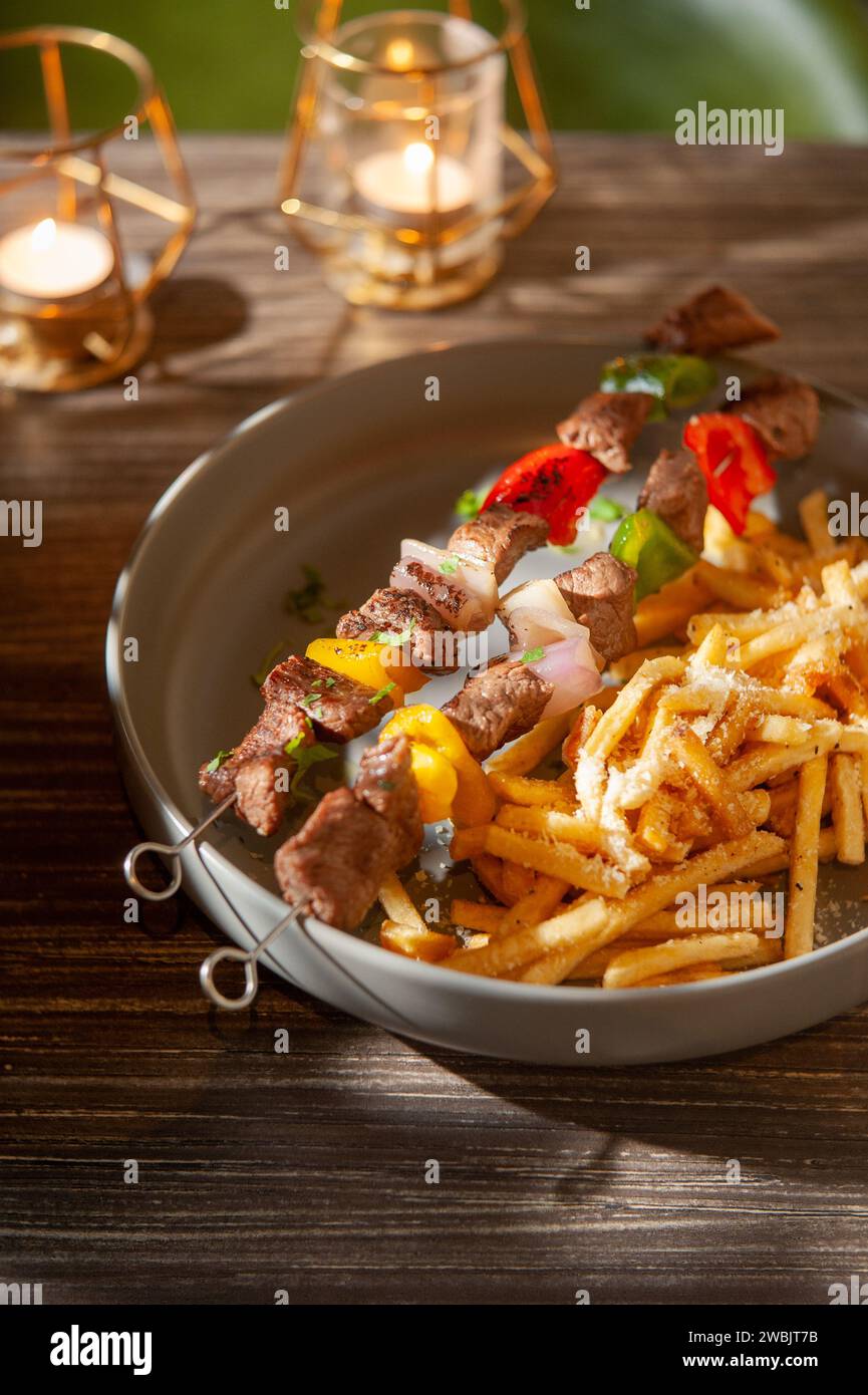 Eine vertikale Nahaufnahme von Fleisch auf einem Spieß mit Pommes frites Stockfoto