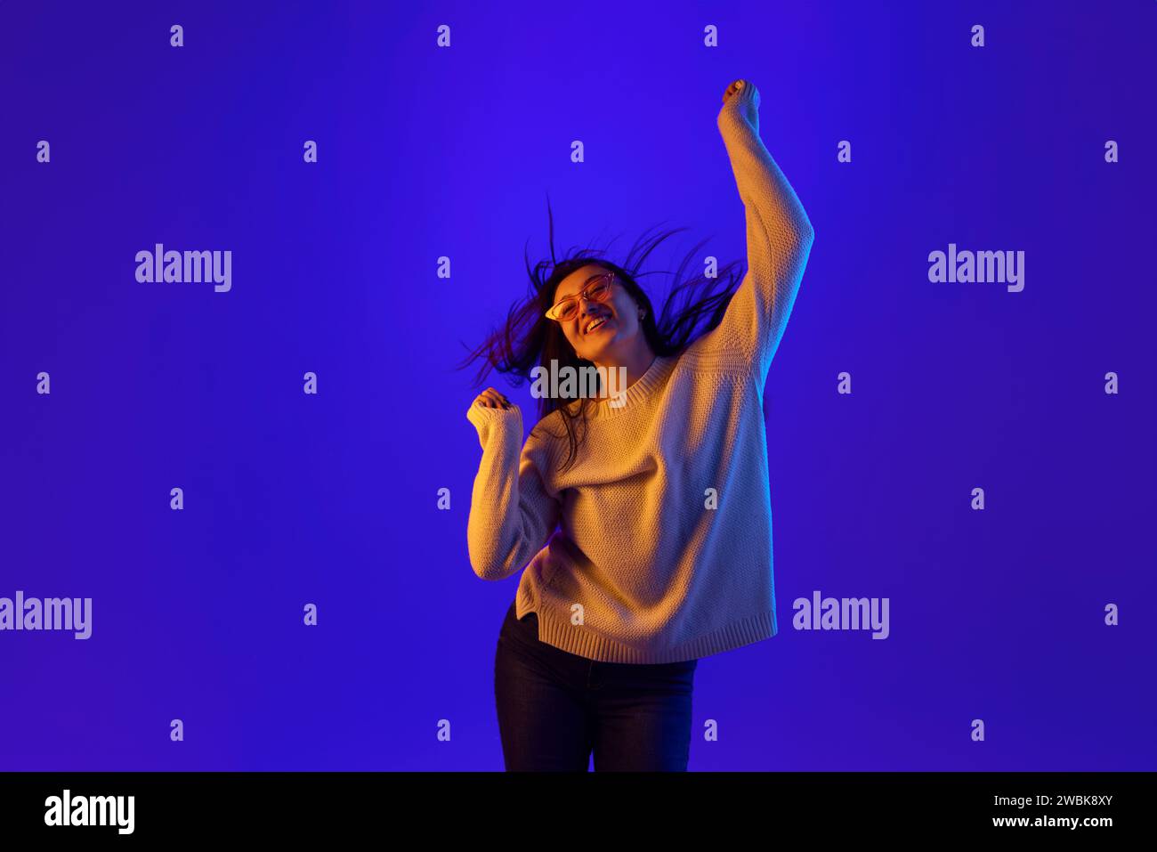 Dynamisches Porträt einer jungen Frau in trendiger Sonnenbrille bewegt sich energetisch rhythmisch und ihr Haar entwickelt sich in Bewegung. Stockfoto