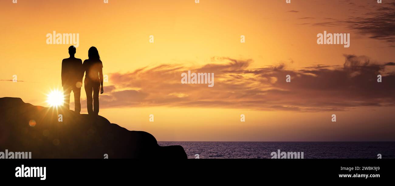 Sihouette von einem Mann und einer Frau auf einer Klippe bei Sonnenuntergang Stockfoto