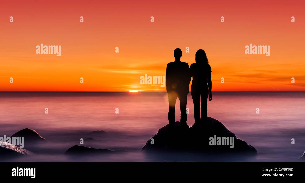 Sihouette von einem Mann und einer Frau auf einer Klippe bei Sonnenuntergang Stockfoto