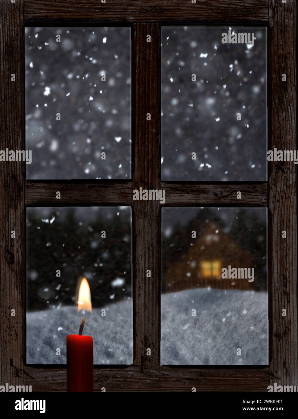 Blick durch ein altes Holzfenster mit einer Kerze im Winter Stockfoto