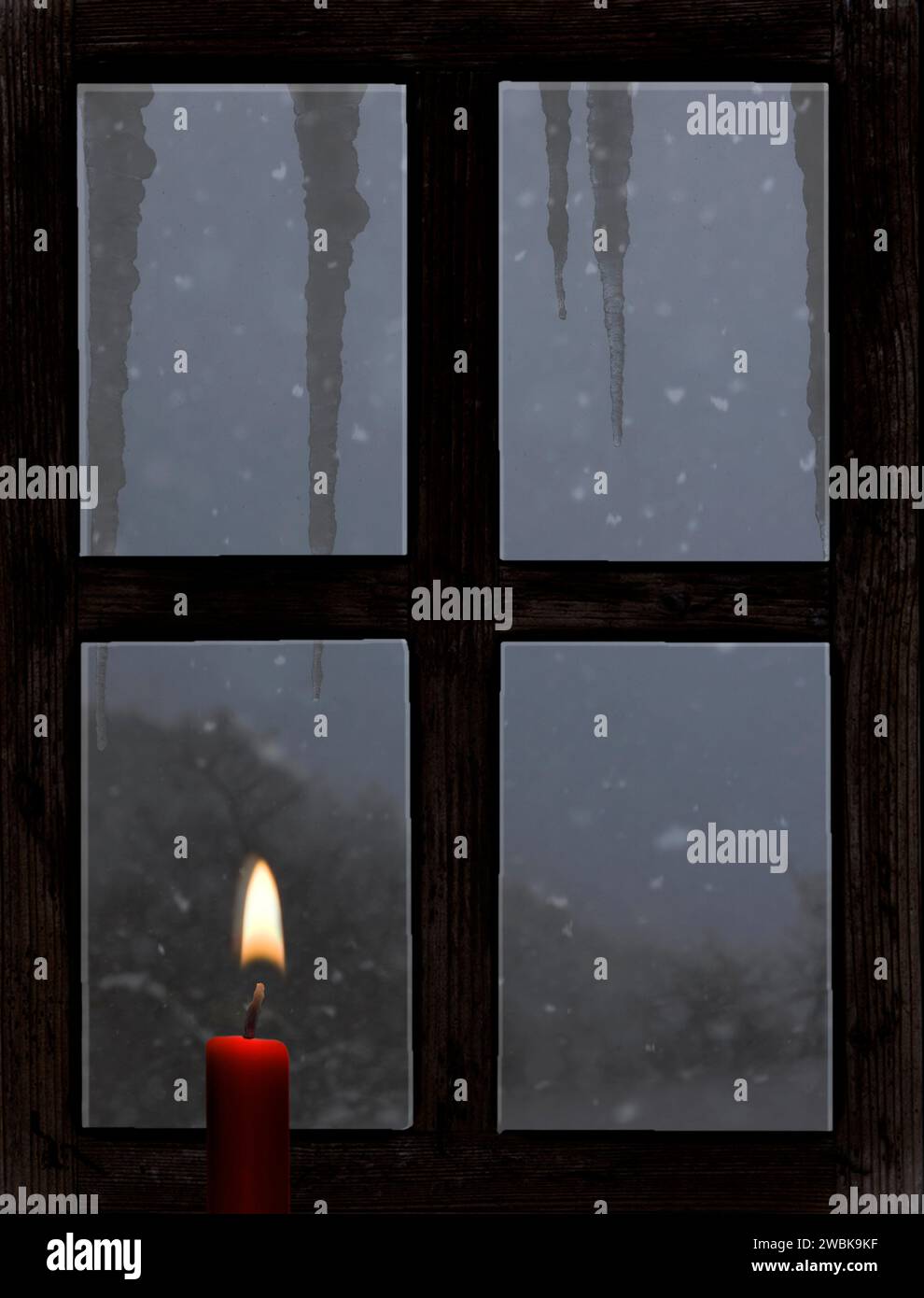 Blick durch ein altes Holzfenster mit einer Kerze im Winter Stockfoto