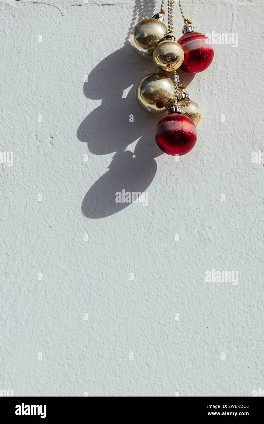 Rote und goldene Weihnachtsbaumkugeln hängen an einer weißen Hauswand in Spanien Stockfoto