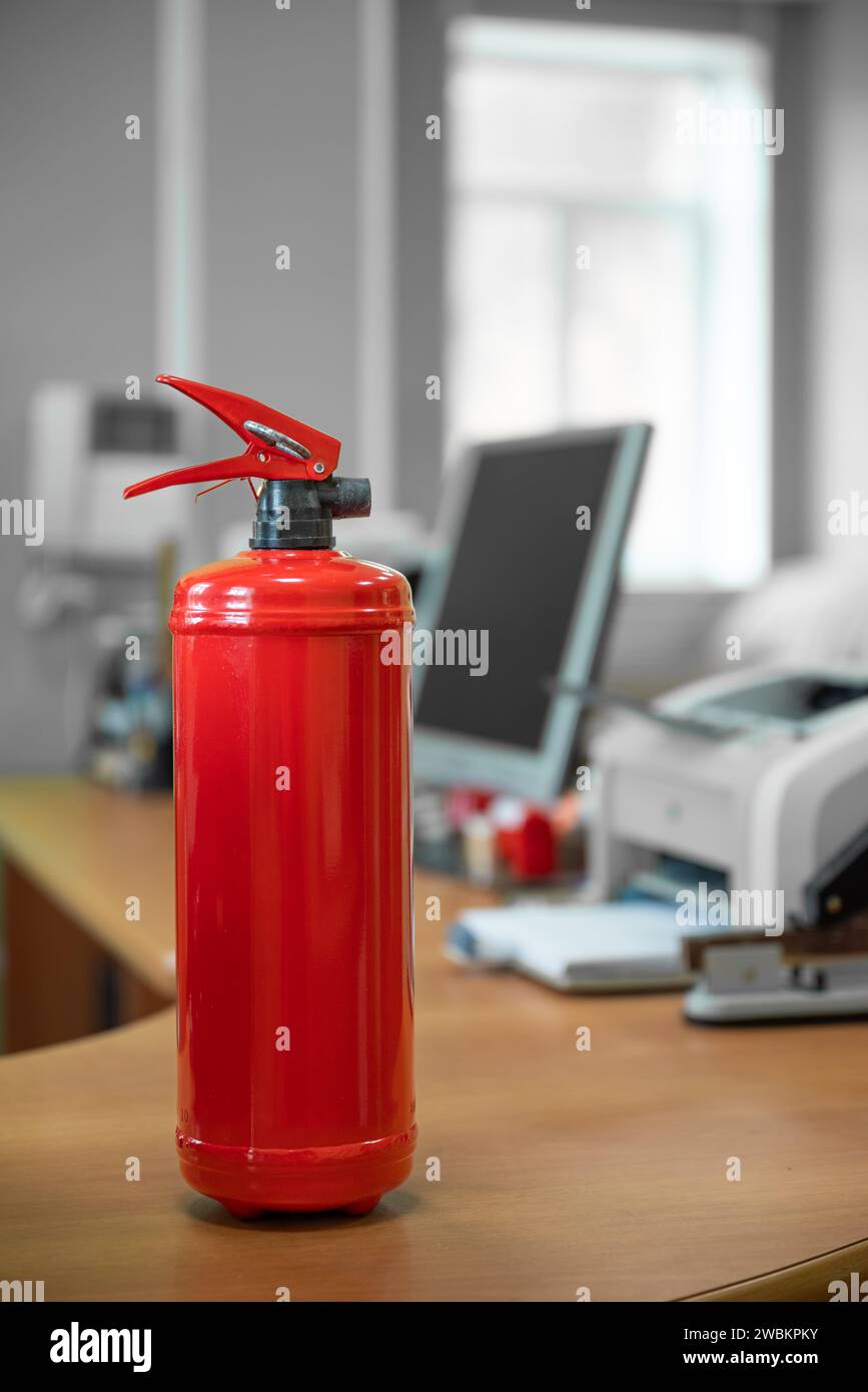 Feuerlöscher in Arbeitsplatz Büro gegen Plain neutralen Hintergrund Stockfoto