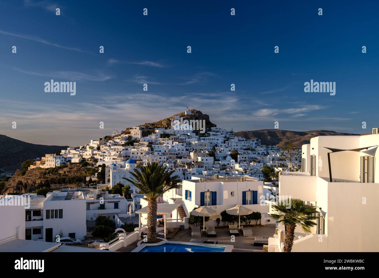 IOS, Griechenland - 14. September 2023 : Blick auf ein malerisches Hotel mit Swimmingpool und das weiß getünchte Dorf iOS Griechenland im Hintergrund Stockfoto