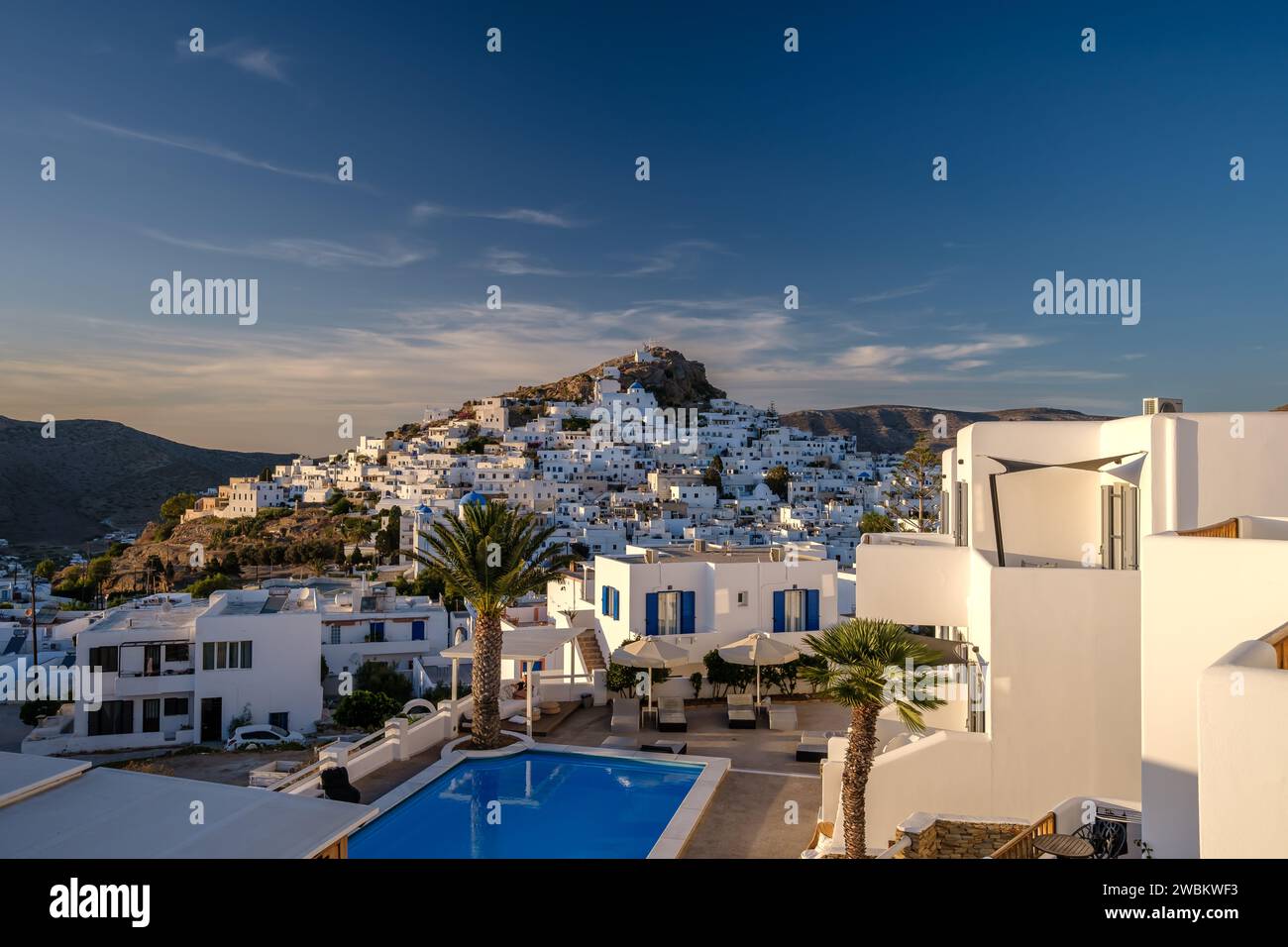 IOS, Griechenland - 14. September 2023 : Blick auf ein malerisches Hotel mit Swimmingpool und das weiß getünchte Dorf iOS Griechenland im Hintergrund Stockfoto