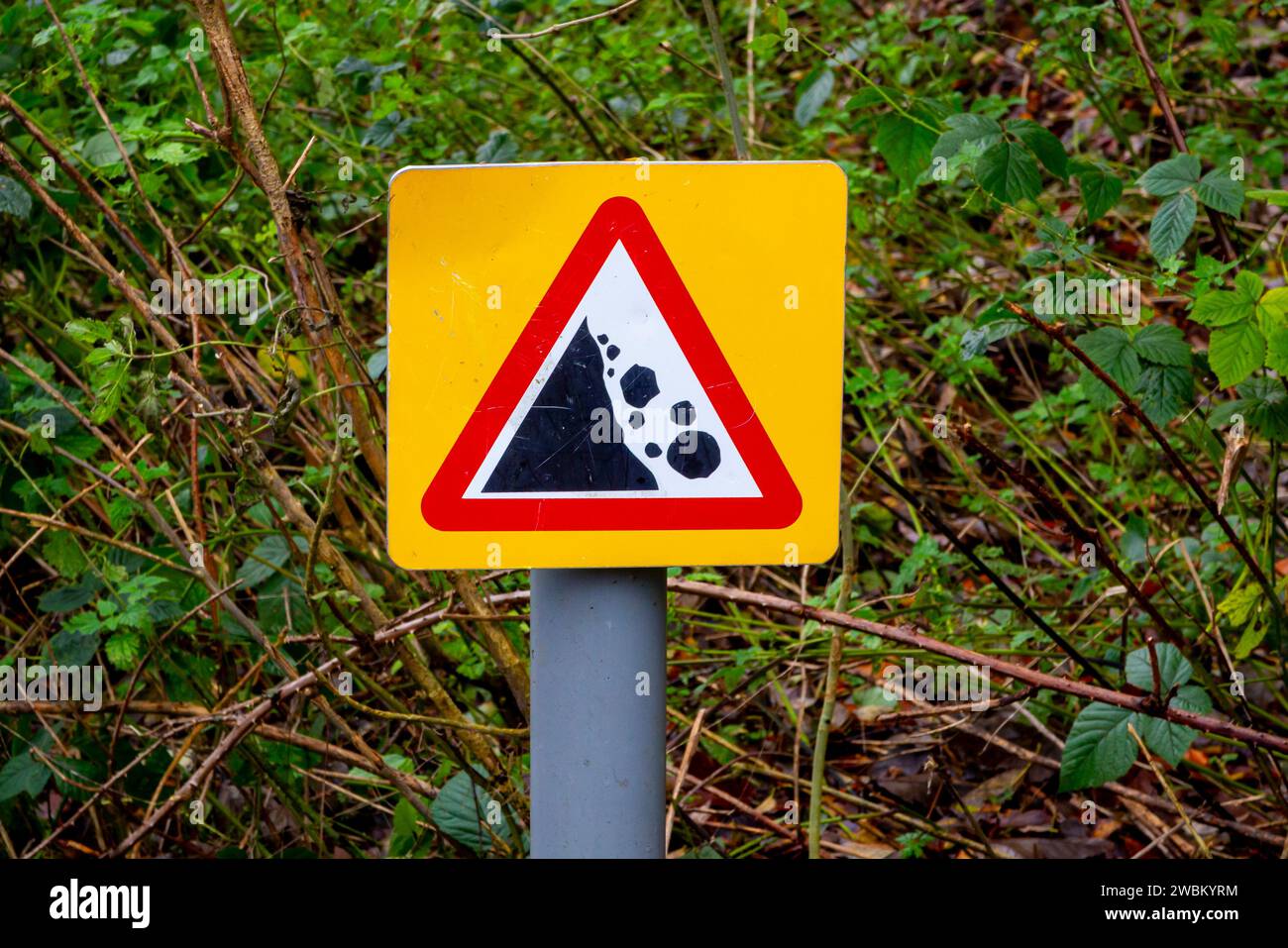 Warnschild mit rotem Dreieck, das auf die Gefahr von herabfallenden Felsen in ländlichen Gebieten hinweist. Stockfoto