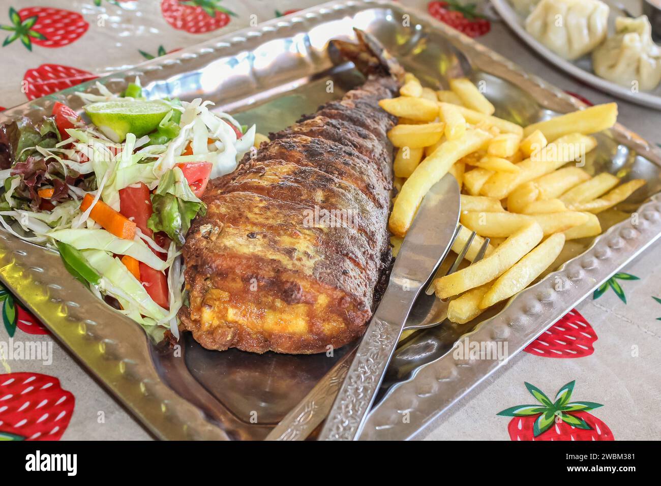 Gebratener Fisch mit Pommes auf einem Teller auf einem rustikalen Tisch. Fischgericht: Frittierter Fisch mit Pommes frites und Gemüse. Niemand, selektiver Fokus Stockfoto