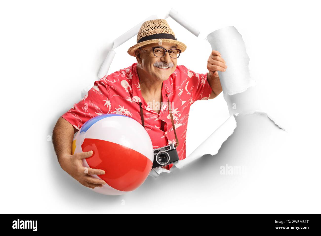 Reifer männlicher Tourist, der durch ein Papierloch blickt und einen Strandball auf weißem Hintergrund hält Stockfoto