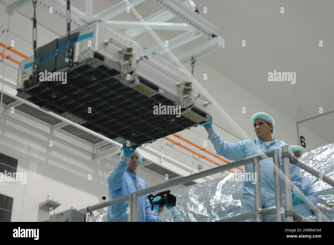 Die Arbeiter der Raumstation-Verarbeitungsanlage heben eine Fliesenbox von dem leichten Mehrzweck-Experiment Support Structure Carrier ab, der mit dem Space Shuttle Discovery von STS-114 zurückgegeben wurde. Die Fliesenbox enthält das detaillierte Test Objective Fliesen Reparatur Kit, das von Astronauten während der Mission getestet wurde. Die Kiste wird zum Johnson Space Center in Houston geschickt. Stockfoto