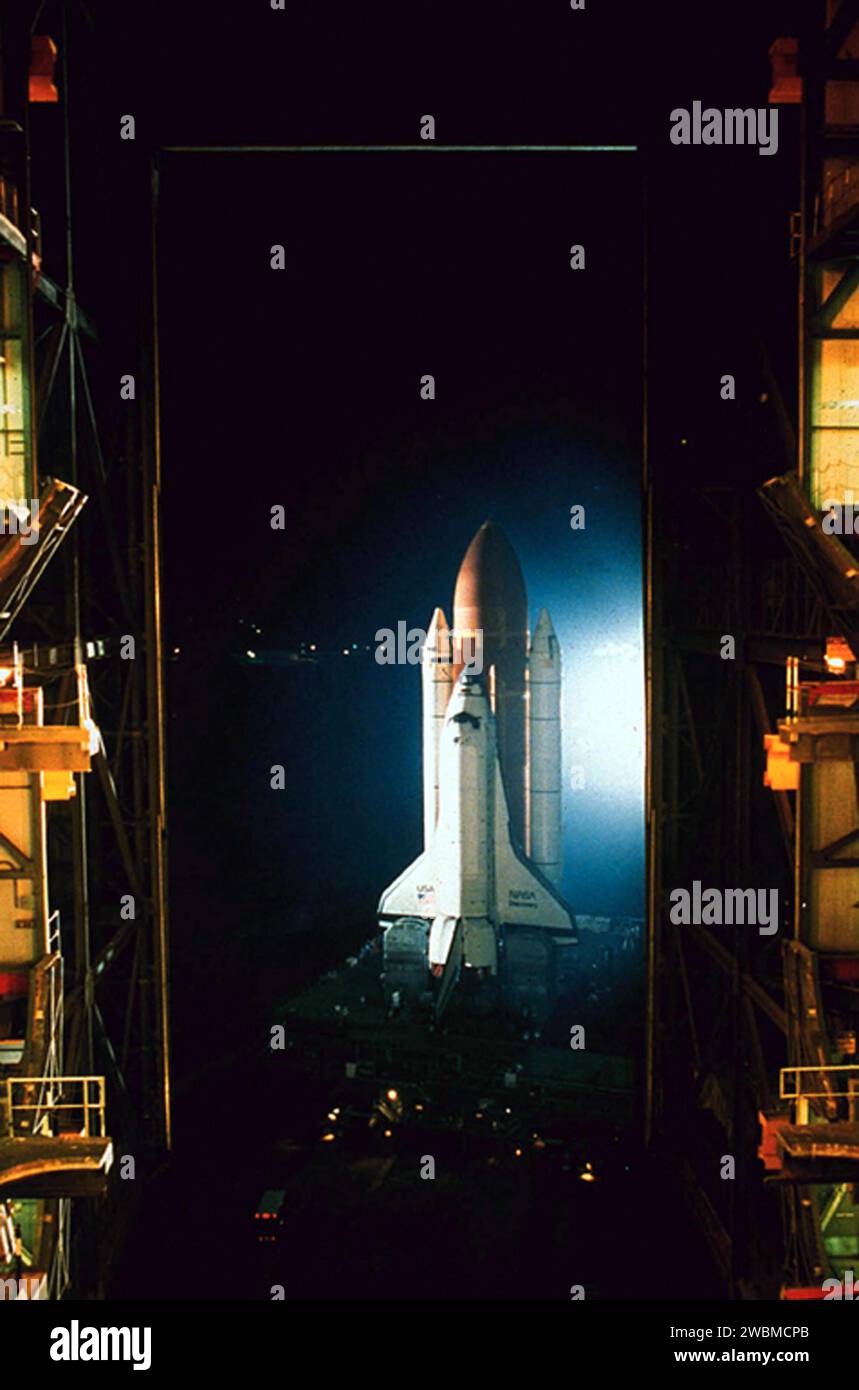 RAUMFAHRTZENTRUM KENNEDY, FLA. -- Ein Blick von der dritten Bucht des Vehicle Assembly Building (VAB) zeigt die Space Shuttle Discovery, die in weißem Xenon-Licht gewaschen wird, als sie nachts von der VAB auf dem Weg zum Stützpunkt 39B abfährt Die Discovery wird für die Mission STS-26 fliegen, die jetzt im September mit ihrer fünfköpfigen Besatzung und der TDRS-C-Nutzlast starten soll. Die erste Bewegung des Shuttles vom VAB zum Stützpunkt kam um 50 Uhr, 4. Juli 1988. Stockfoto