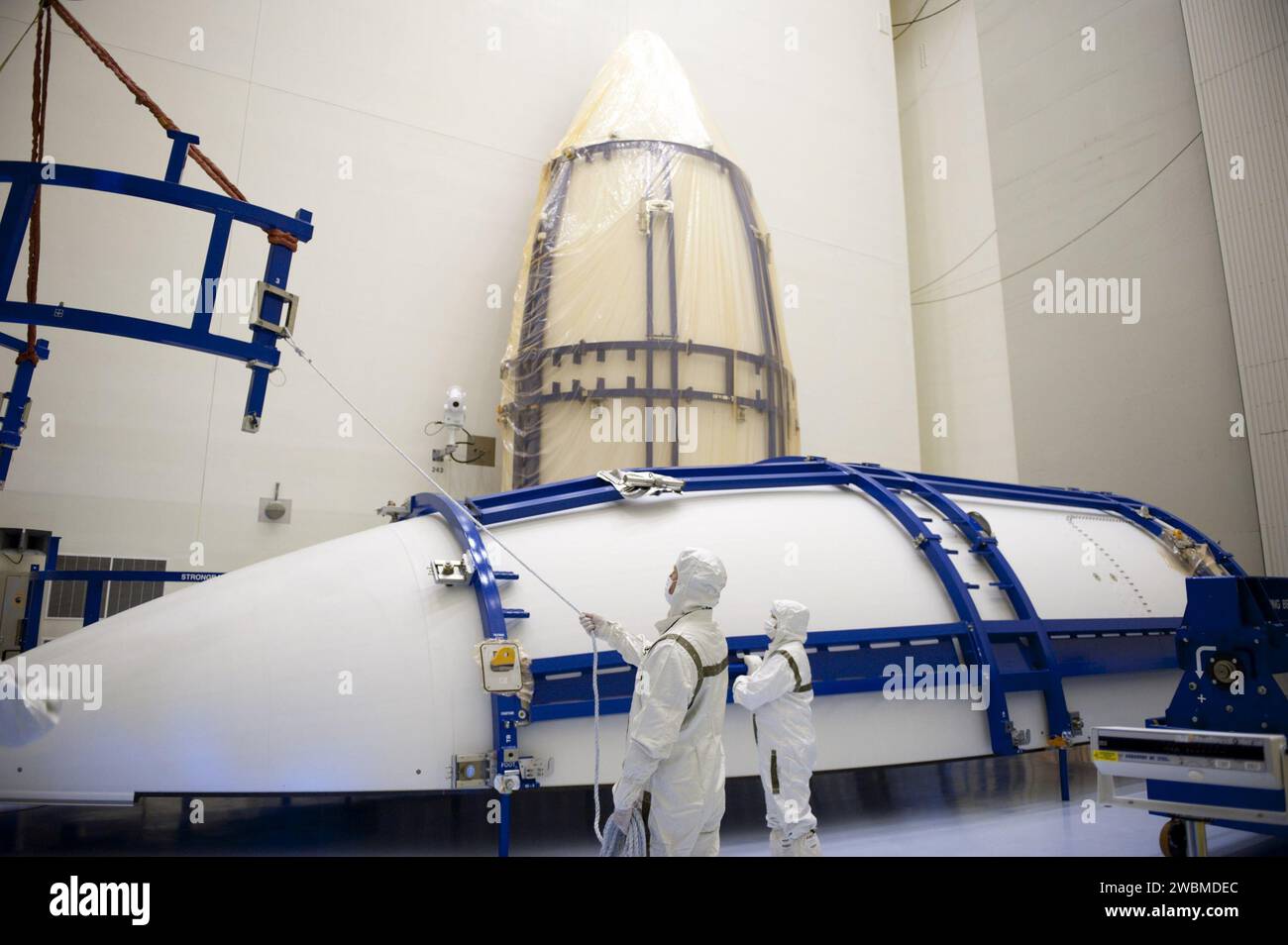 CAPE CANAVERAL, Fla. -- in der Payload Hazardous Service Facility im Kennedy Space Center der NASA in Florida führen Techniker der United Launch Alliance eine Hebevorrichtung zur Hälfte der Atlas V Nutzlastverkleidung für die Mission Mars Science Laboratory (MSL) der NASA. Die Verkleidung wurde freigelegt und Vorbereitungen zur Reinigung sind im Gange, um die Anforderungen der NASA für den Planetenschutz zu erfüllen. Im Hintergrund befindet sich die andere Hälfte der Verkleidung, die noch offen ist. Die Verkleidung schützt das Raumfahrzeug vor dem Einfluss von aerodynamischem Druck und Erwärmung während des Aufstiegs. Obwohl sie einmal aus dem Raum geworfen wurden Stockfoto