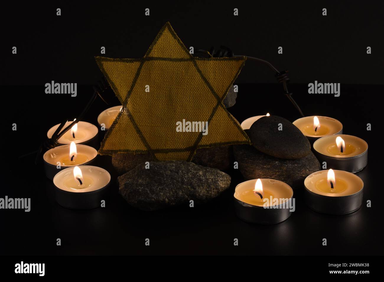 Steine, David-Stern, Kerzen, Stacheldraht, Israel-Flagge auf dunklem Hintergrund. Holocaust-Konzept. Stockfoto