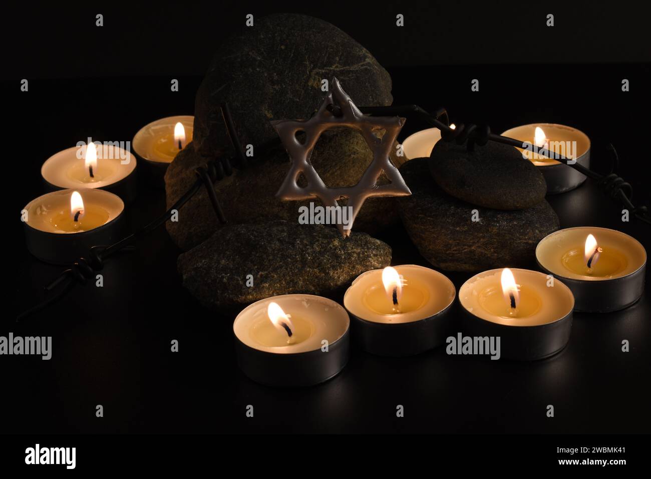 Steine, David-Stern, Kerzen, Stacheldraht, Israel-Flagge auf dunklem Hintergrund. Holocaust-Konzept. Stockfoto