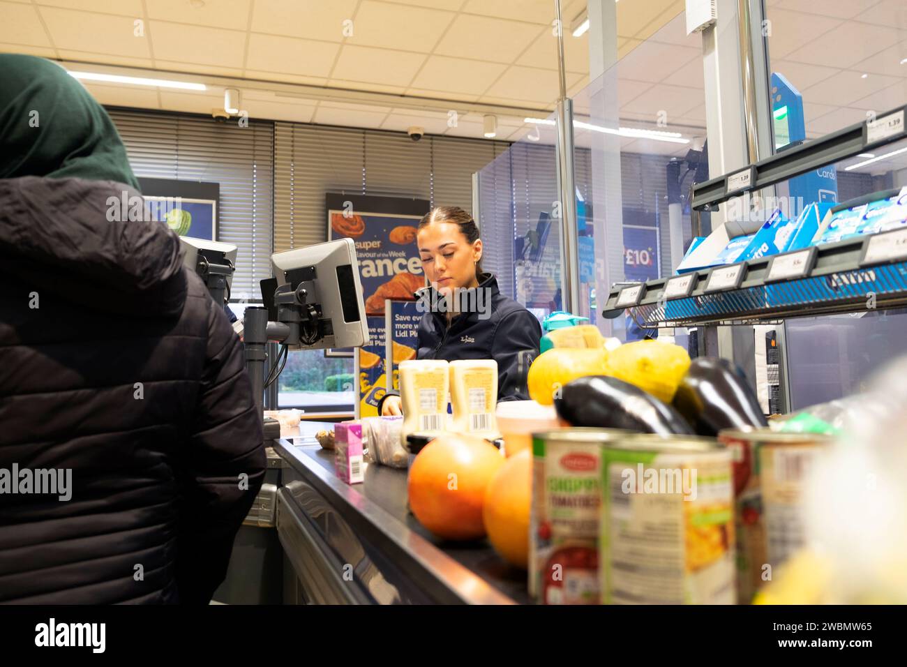 Junge Mitarbeiterin, die an der Kasse im Lidl Supermarkt 2024 in Großbritannien arbeitet, KATHY DEWITT Stockfoto