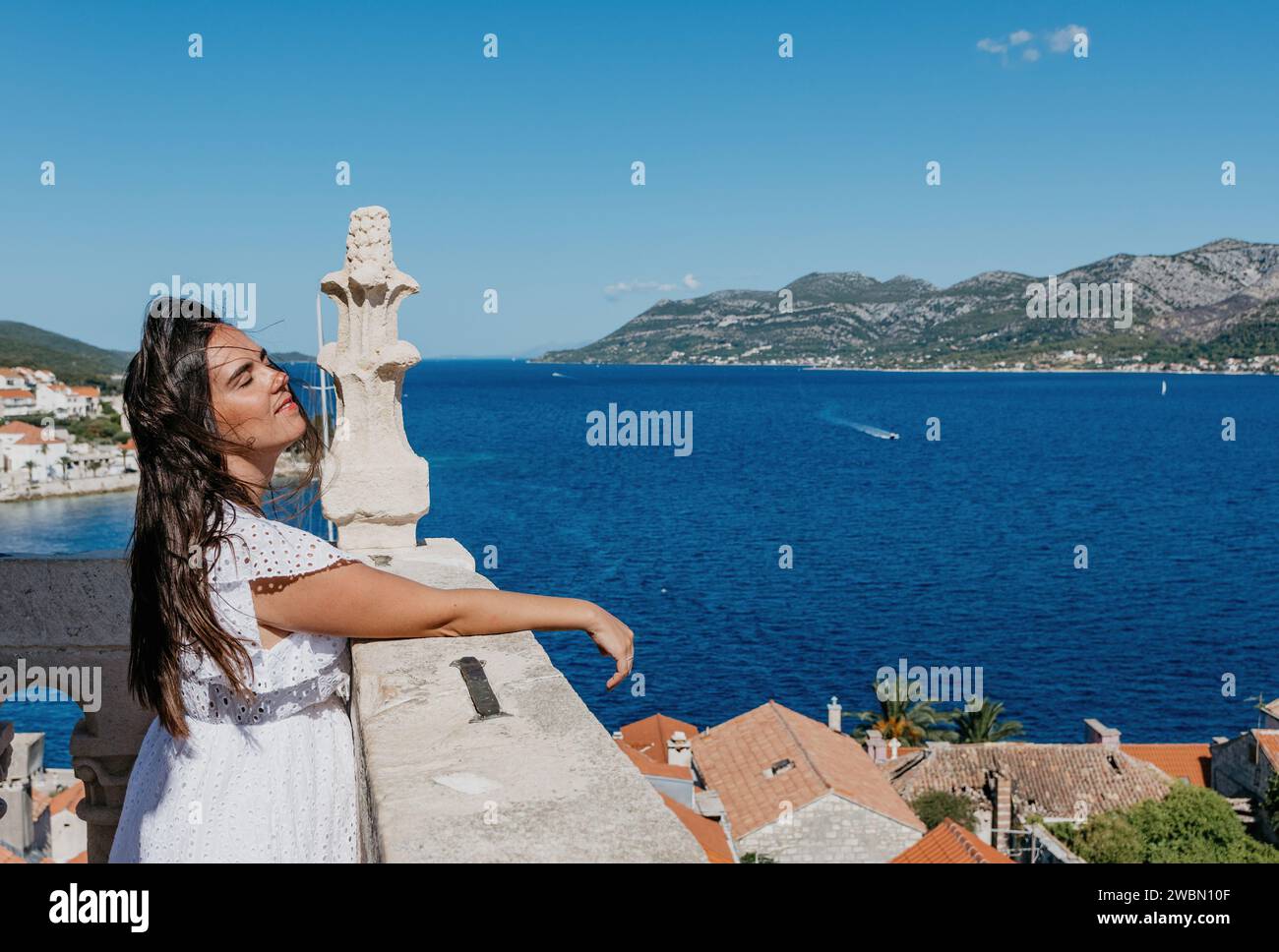 Eine attraktive junge Frau in einem eleganten weißen Kleid posiert für ein fesselndes Foto Stockfoto