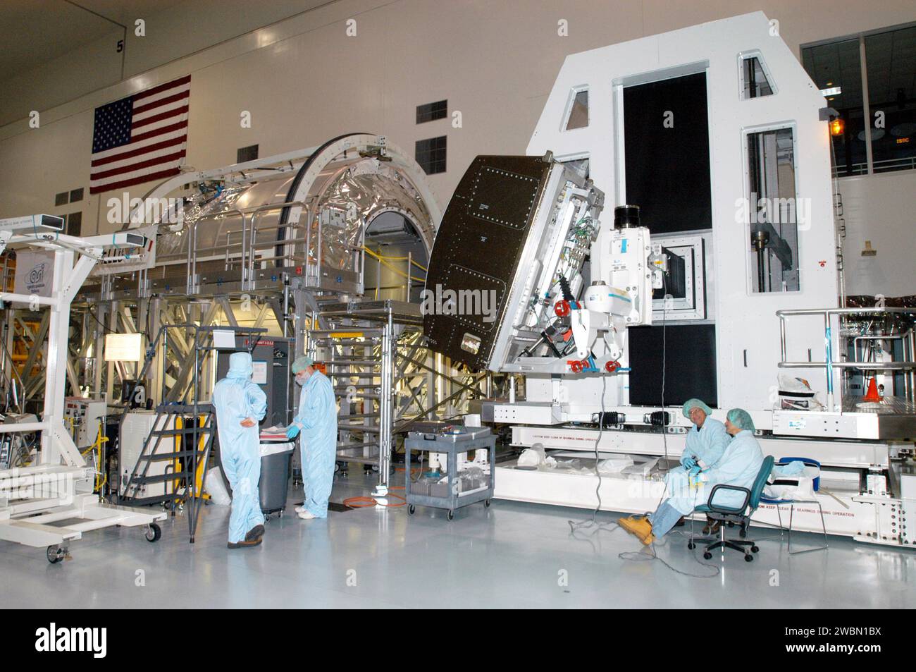 RAUMFAHRTZENTRUM KENNEDY, FLA. - In der Raumstation-Verarbeitungsanlage bereiten sich die Arbeiter darauf vor, das wissenschaftliche Rack der Human Research Facility-2 (HRF-2) an der Rack-Einsteckvorrichtung anzubringen. HRF-2 wird im Multifunktions-Logistikmodul Raffaello (links) für den Flug mit der Mission STS-114 des Space Shuttle Discovery zur Rückkehr zum Flug installiert. Die HRF-2 wird der Internationalen Raumstation zusätzliche biomedizinische Instrumente und Forschungskapazitäten zur Verfügung stellen. HRF-1, seit Mai 2001 im US-Labor installiert, enthält ein Ultraschallgerät und einen Gasanalysator. Beide Racks bieten strukturelle, elektrische und thermische Leistung Stockfoto