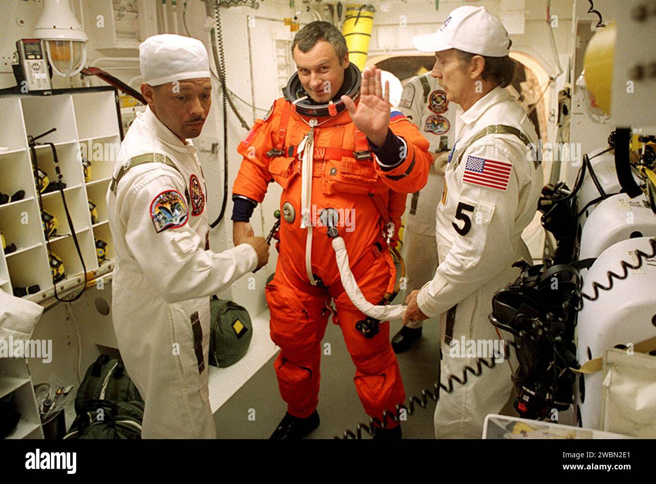 KENNEDY SPACE CENTER, FLORIDA. Vladimir Dezhurov, Mitglied der Expedition, winkt, wie er mit seinem Start- und Einstiegsanzug unterstützt wird, bevor er zum Start in das Space Shuttle Discovery einsteigt. Ihm helfen (links) John Herrington und (rechts) der US-amerikanische Mechaniker Al Schmidt. Die Nutzlast der STS-105-Mission zur Internationalen Raumstation umfasst den dritten Flug des in Italien gebauten Mehrzwecklogistik-Moduls Leonardo, der zusätzliche wissenschaftliche Racks, Ausrüstung und Vorräte für die Raumstation und den EAS-Tank (Early Ammonia Servicer) liefert. Das EAS, Stockfoto