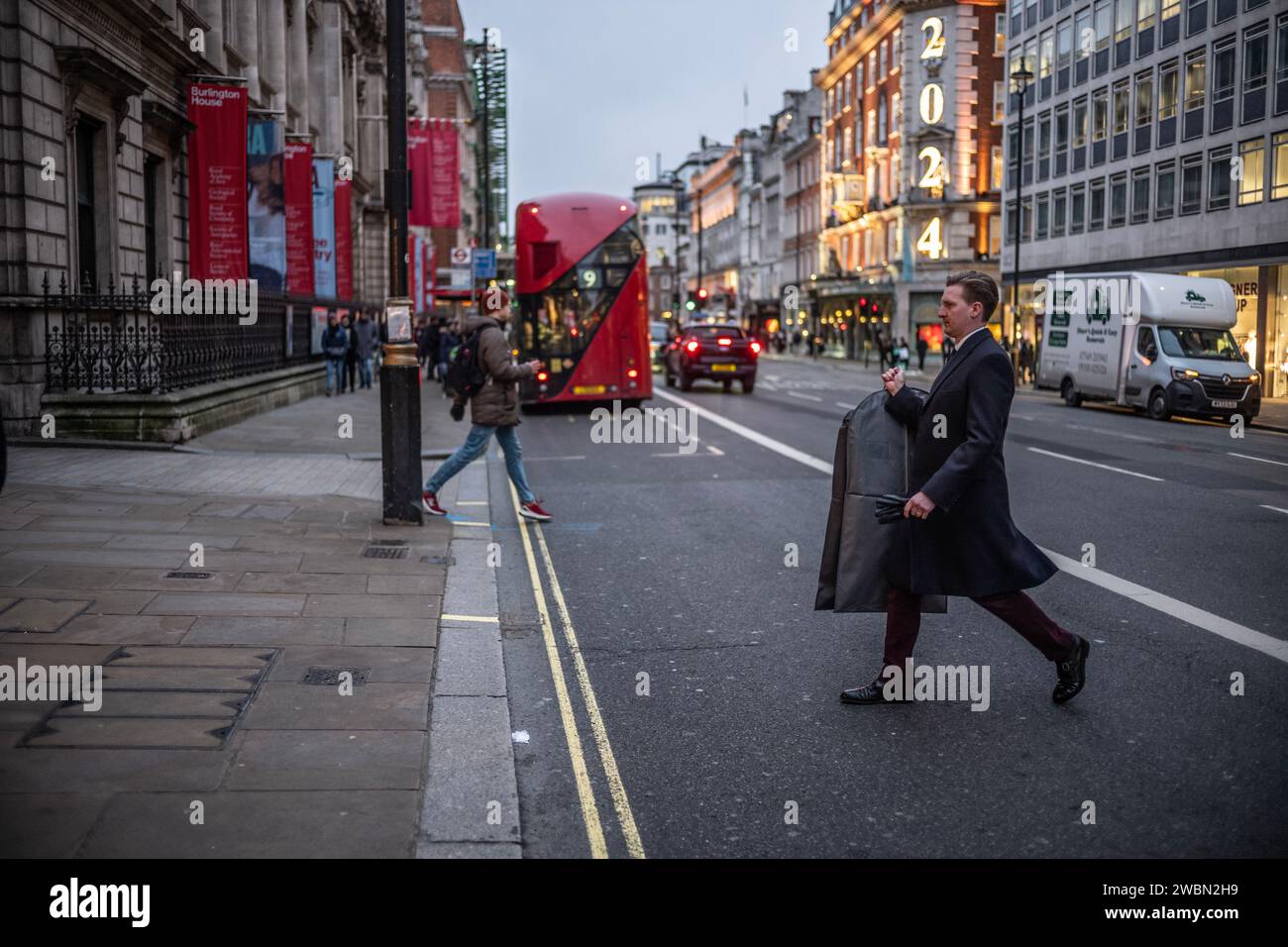 Geschäftsmann, der einen Anzug mit Tasche über Piccadilly im Herzen des Londoner Stadtteils Mayfair in London, Großbritannien, hält Stockfoto