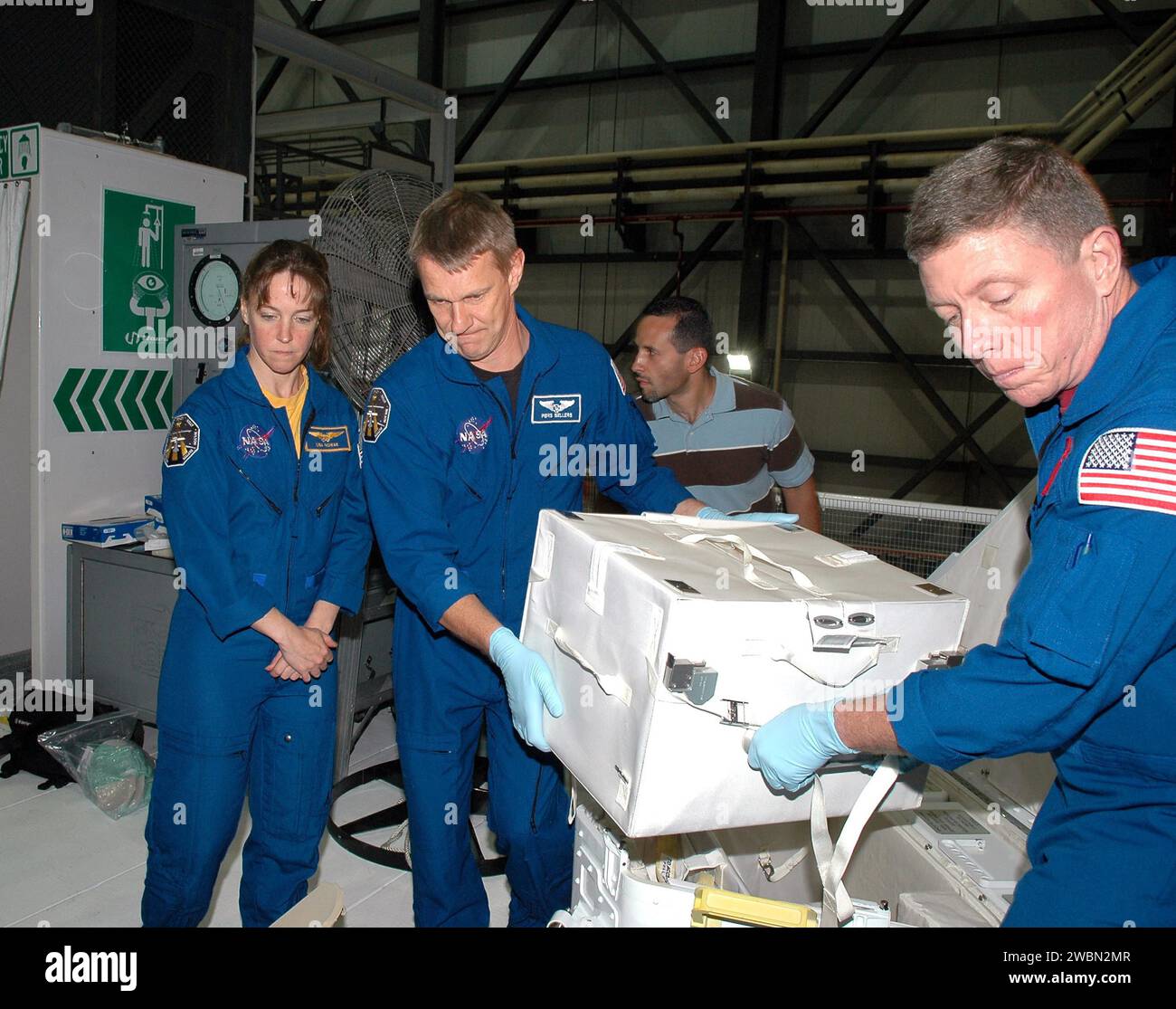 RAUMFAHRTZENTRUM KENNEDY, FLA. - In der Orbiter Processing Facility im Kennedy Space Center der NASA entladen Astronauten der zweiten Return to Flight Mission, STS-121, das Fliesenreparaturkit, um sich die Hardware genauer anzusehen, mit der sie auf der Mission arbeiten werden. Die Crew-Mitglieder auf diesem Foto sind von links nach rechts die Mission Specialists Lisa Nowak, Piers J. Sellers und Michael E. Fossum. Die Crew ist bei KSC, um am Crew Equipment Interface Test (CEIT) teilzunehmen. Während des CEIT hat die Crew die Möglichkeit, einen praktischen Einblick in den Orbiter und die Ausrüstung zu erhalten, mit der sie bei ihren Missionen arbeiten wird. Miss Stockfoto