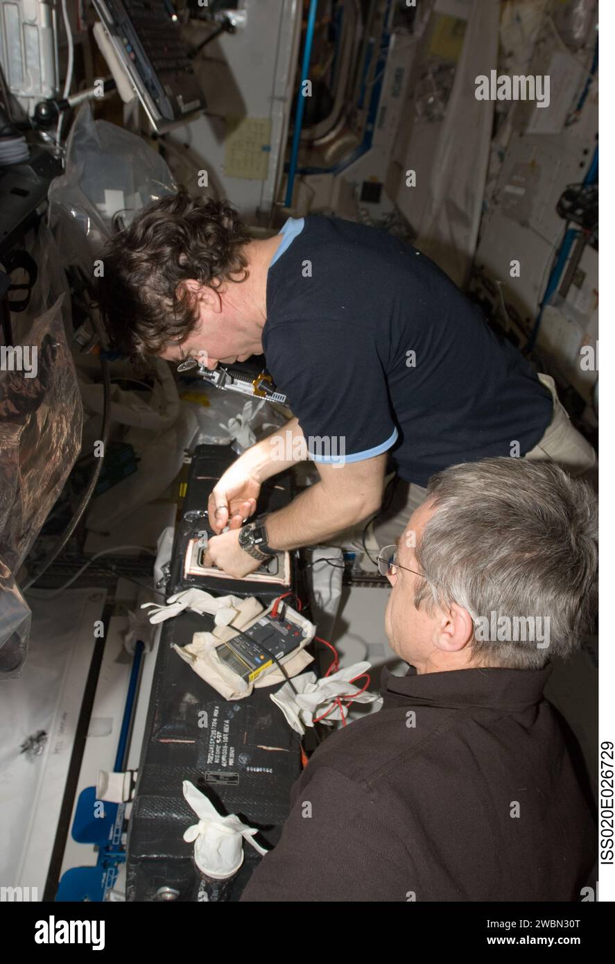 NASA-Astronaut Michael Barratt und der kanadische Astronaut Robert Thirsk, Flugingenieure der Expedition 20, führen Drahtabschnitte und Sicherungsverfahren an der Carbon Dioxide Removal Assembly im Destiny-Labor der Internationalen Raumstation durch, um kurzgeschlossene erhitzte Drähte zu beheben. Stockfoto