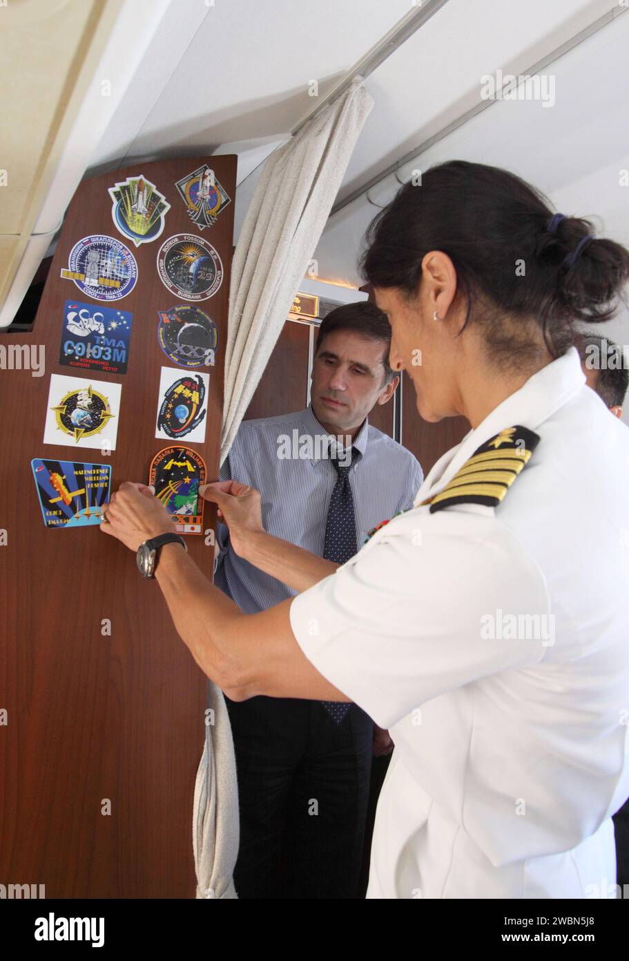 Die NASA-Flugingenieurin Sunita Williams befestigte ein Besatzungsfeld an der Flugzeugkabine, bevor sie, Sojus-Kommandant Juri Malenchenko und JAXA-Flugingenieur Aki Hoshide von Star City in Russland zum Baikonur Cosmodrome flogen, um vor dem Start für die Sojus-TMA-05M-Mission zur ISS zu trainieren. Stockfoto