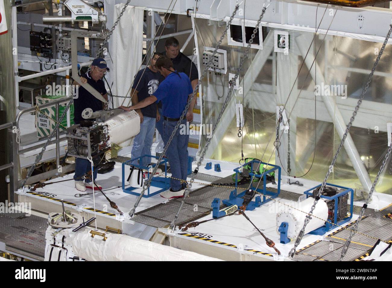 CAPE CANAVERAL, Fla. – Innerhalb der Orbiter Processing Facility-2 im Kennedy Space Center der NASA in Florida überwachen Techniker den Fortschritt, während ein Spezialkran eine der drei Brennstoffzellen aus dem Space Shuttle Atlantis’ hebt, um sie auf einer speziellen Plattform zu sichern. Alle Flüssigkeiten werden aus den Brennstoffzellen abgelassen. Die Wasserstoff- und Sauerstoff-Dewars, die den Brennstoffzellen Reaktanten zuführen, verbleiben im mittleren Körper von Atlantis und werden mit inerten Gasen gespült und abgelassen. Die Arbeit ist Teil der Übergangs- und Pensionierung des Shuttles Atlantis. Der Orbiter wird auf die Di vorbereitet Stockfoto