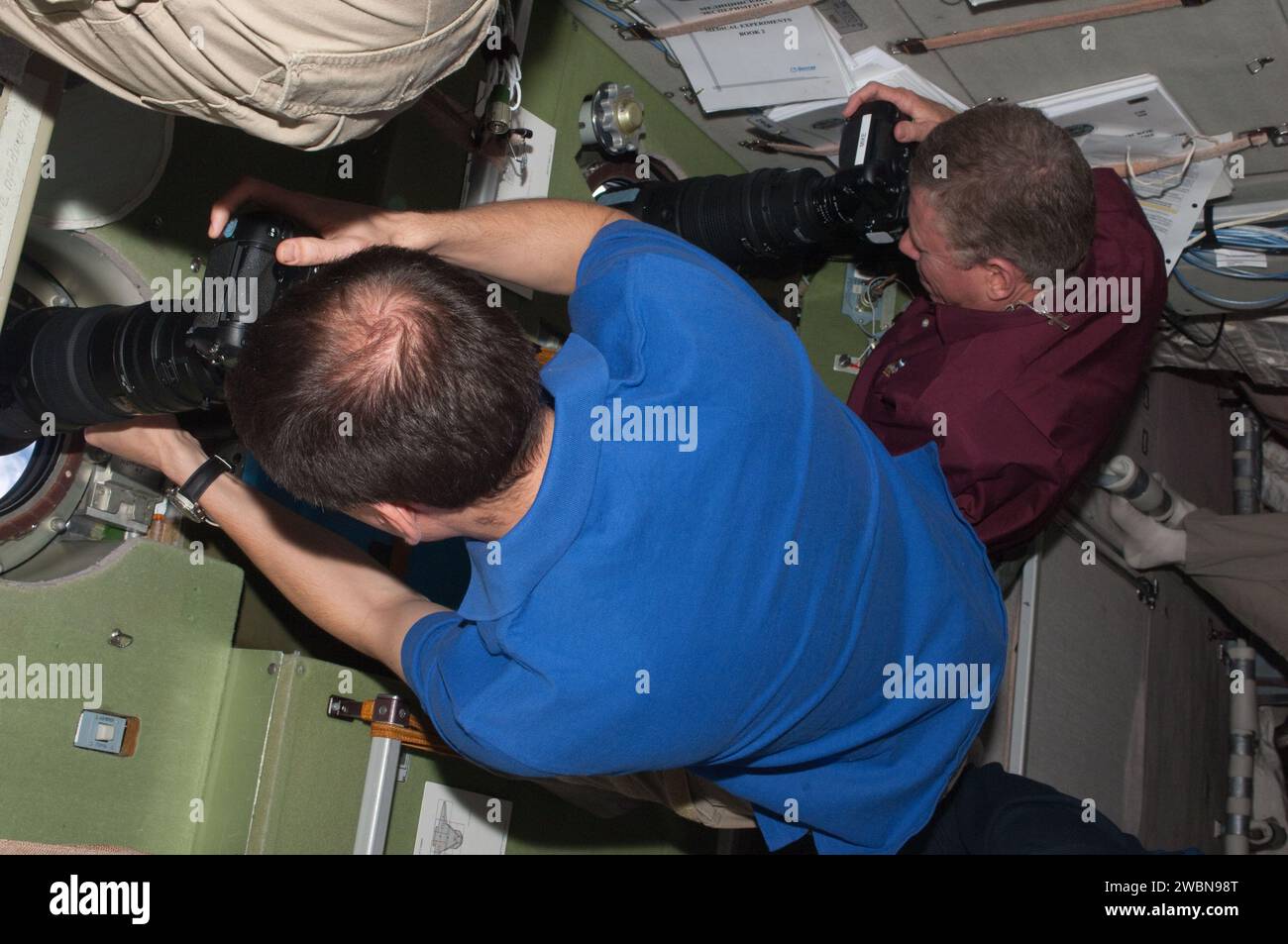 Der russische Kosmonaut Sergei Volkow und der NASA-Astronaut Mike Fossum fotografieren das Space Shuttle Atlantis durch das Fenster des Zvezda-Servicemoduls während des Rendezvous-Betriebs am 12. Juli 2011. Stockfoto