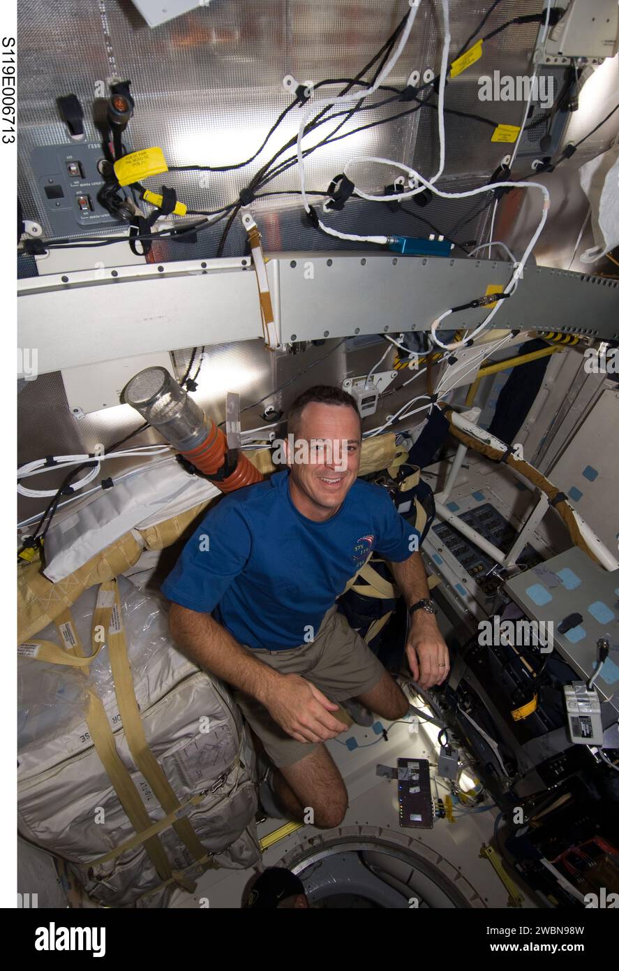 S119-E-006713 (20. März 2009) --- Astronaut Richard Arnold, STS-119-Missionsspezialist, scheint fast von der Decke des mittleren Deck der Discovery aufgehängt zu sein, als er eine Aufgabe am 6. Fluchttag erledigt. Stockfoto