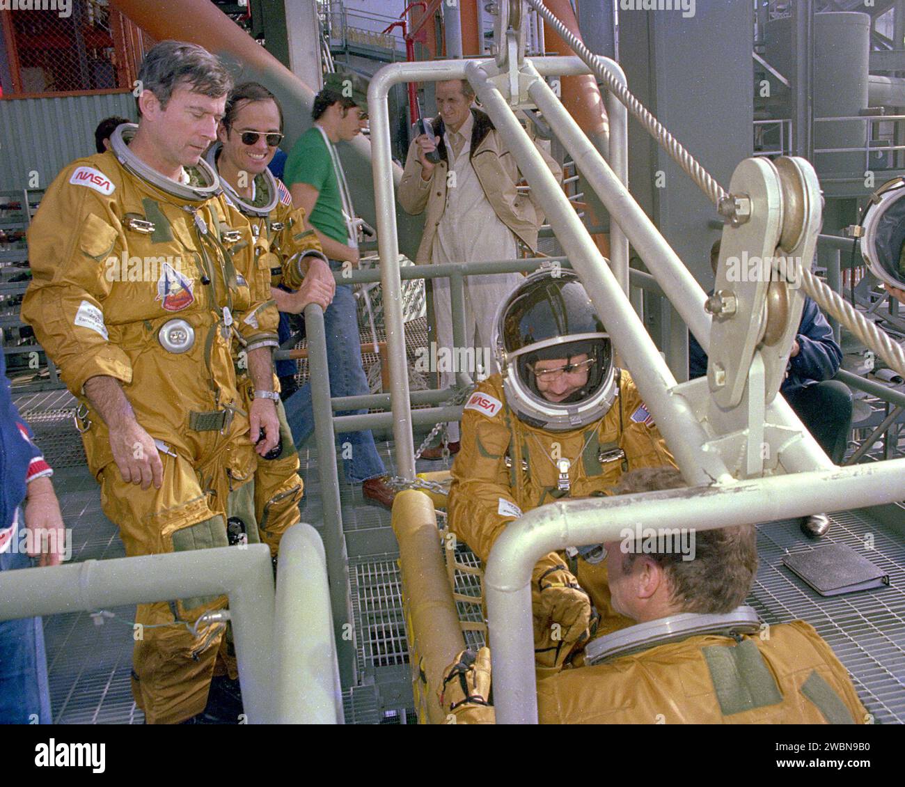 RAUMFAHRTZENTRUM KENNEDY, FLA. - Space Shuttle Commander John Young und Pilot Bob Crippen beobachten, wie die Besatzungsmitglieder Richard True und Joe Engle an Bord des Notauflagesystems gehen, das als Gleitdraht bekannt ist. Das Schiebedrahtsystem ermöglicht ein schnelles Entweichen von den oberen Startplattformen im Falle eines schweren Notfalls. Die Flugbesatzungen trugen die Raumanzüge und andere Ausrüstung, die während einer Mission getragen werden sollten, aber Sandsäcke wurden verwendet, um das Gewicht der Fahrer in den Gleitdraht-Baskeets während des Trainings zu verdoppeln. Stockfoto