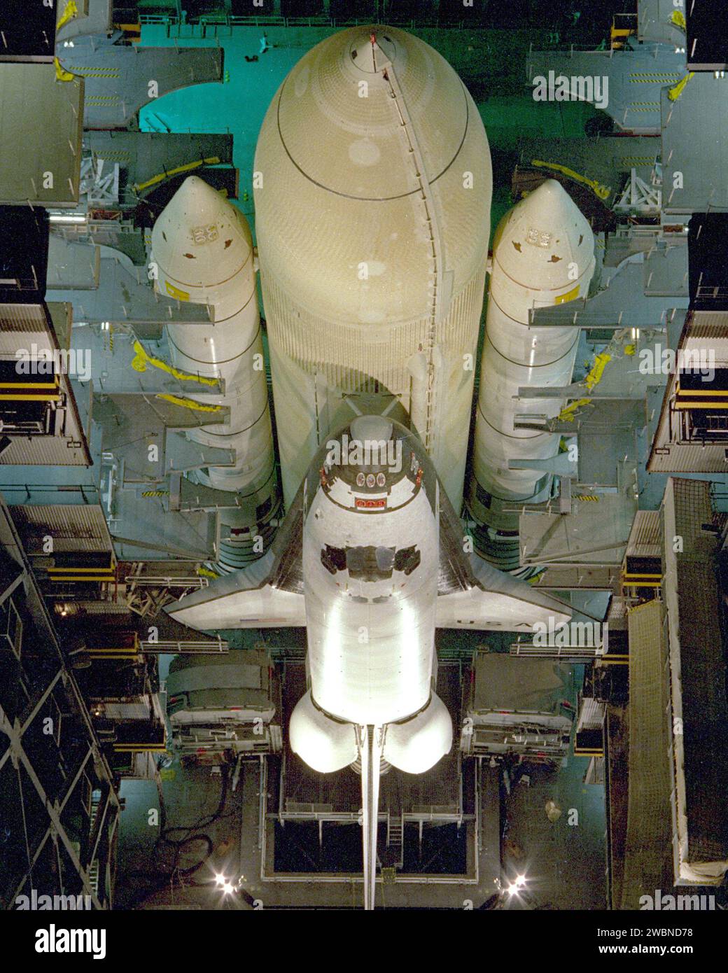 RAUMFAHRTZENTRUM KENNEDY, FLA. - Die Montage des ersten Space Shuttle-Fahrzeugs, das im März 1981 seinen ersten orbitalen Testflug machen soll, wurde heute mit der Paarung des Orbiter Columbia mit seinem externen Tank in der High Bay 3 des Fahrzeugmontagegebäudes abgeschlossen. Columbia, das hier noch an der Hebeschlinge befestigt ist, wurde am 24. November in die VAB verlegt, nachdem Tests und Fliesen in der benachbarten Orbiter Processing Facility durchgeführt wurden. Die anderen Shuttle-Komponenten, die zwei festen Raketenverstärker und der externe Treibstofftank, wurden auf der Mobile Launcher Platform in High Bay 3 gestapelt Stockfoto