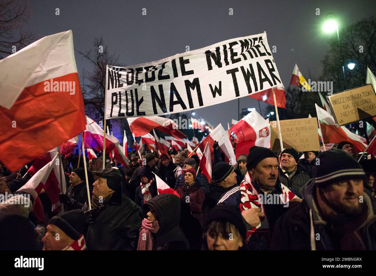 Die Demonstranten halten während der Demonstration ein Banner mit der Aufschrift "Deutsche spucken uns nicht ins Gesicht". Polens rechte Opposition, frustriert über den jüngsten Machtverlust, forderte seine Anhänger auf, gegen die Schritte der neuen pro-europäischen Regierung zu protestieren, die Kontrolle über die staatlichen Rundfunkanstalten und die staatliche Nachrichtenagentur zu übernehmen. Die Partei Recht und Gerechtigkeit (PiS), die acht Jahre lang regierte, bevor sie die Parlamentswahlen im Oktober verlor, rief zu einem Protest unter dem Motto „Protest der Freien Polen“ (Protest Wolnych Polakow) vor dem parlament auf. Sie stellte den Protest als Verteidigung der Demokratie dar Stockfoto