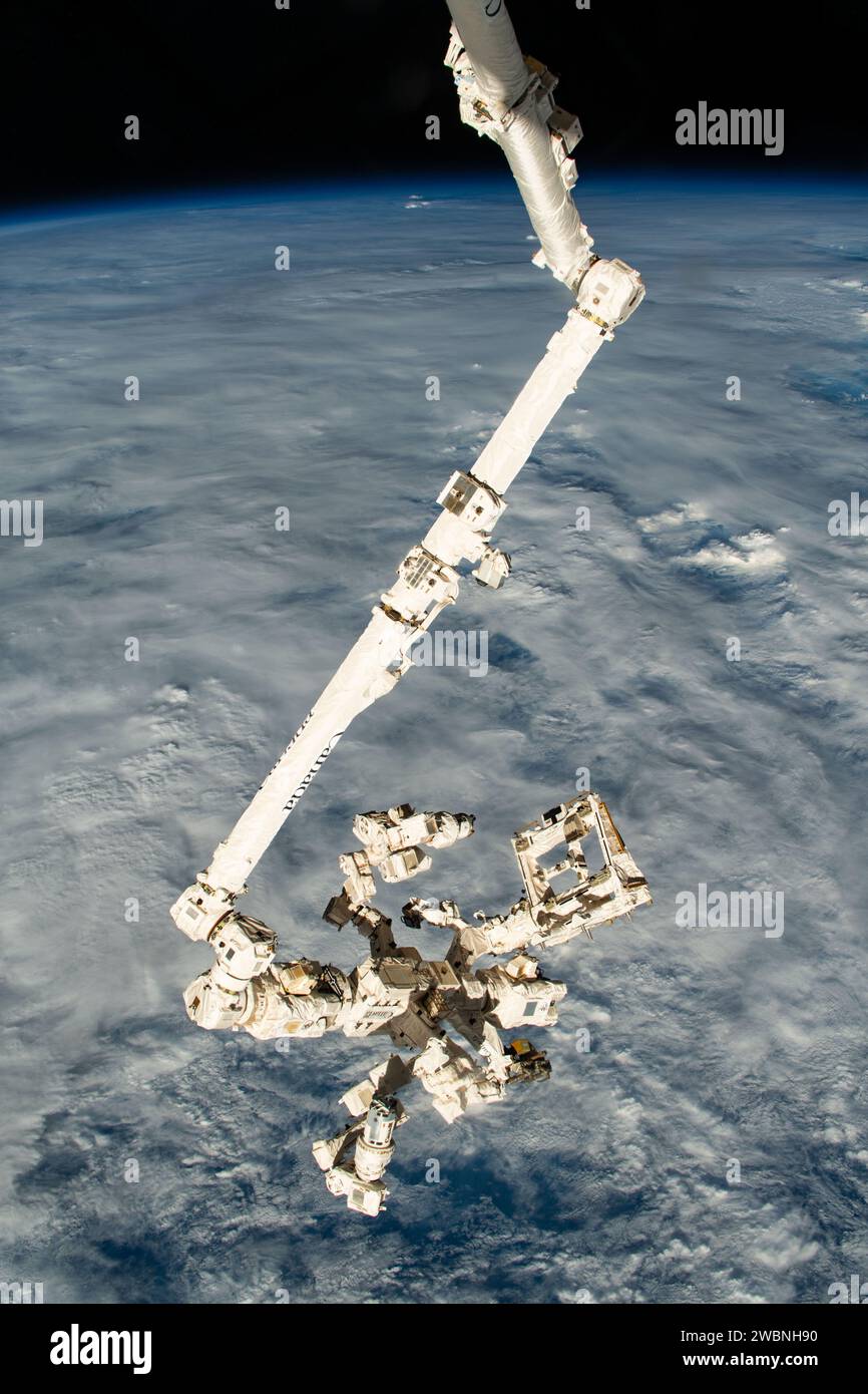 Iss070e025899 (15. November 2023) --- der Canadarm2 Roboterarm mit seiner fein abgestimmten Roboterhand, auch bekannt als Dextre, erstreckt sich vertikal von der Internationalen Raumstation, als er 261 Meilen über einem bewölkten Pazifik nördlich von Papua-Neuguinea umkreiste. Stockfoto