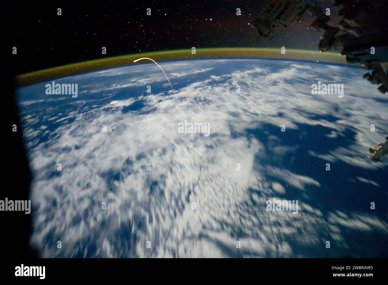 Fotografiert von Expedition 28 an Bord der ISS am 21. Juli 2011, kehrt das Space Shuttle Atlantis zur Erde zurück und erscheint über Wolken und Lichtern der Stadt mit schwachem Luftschein. Stockfoto