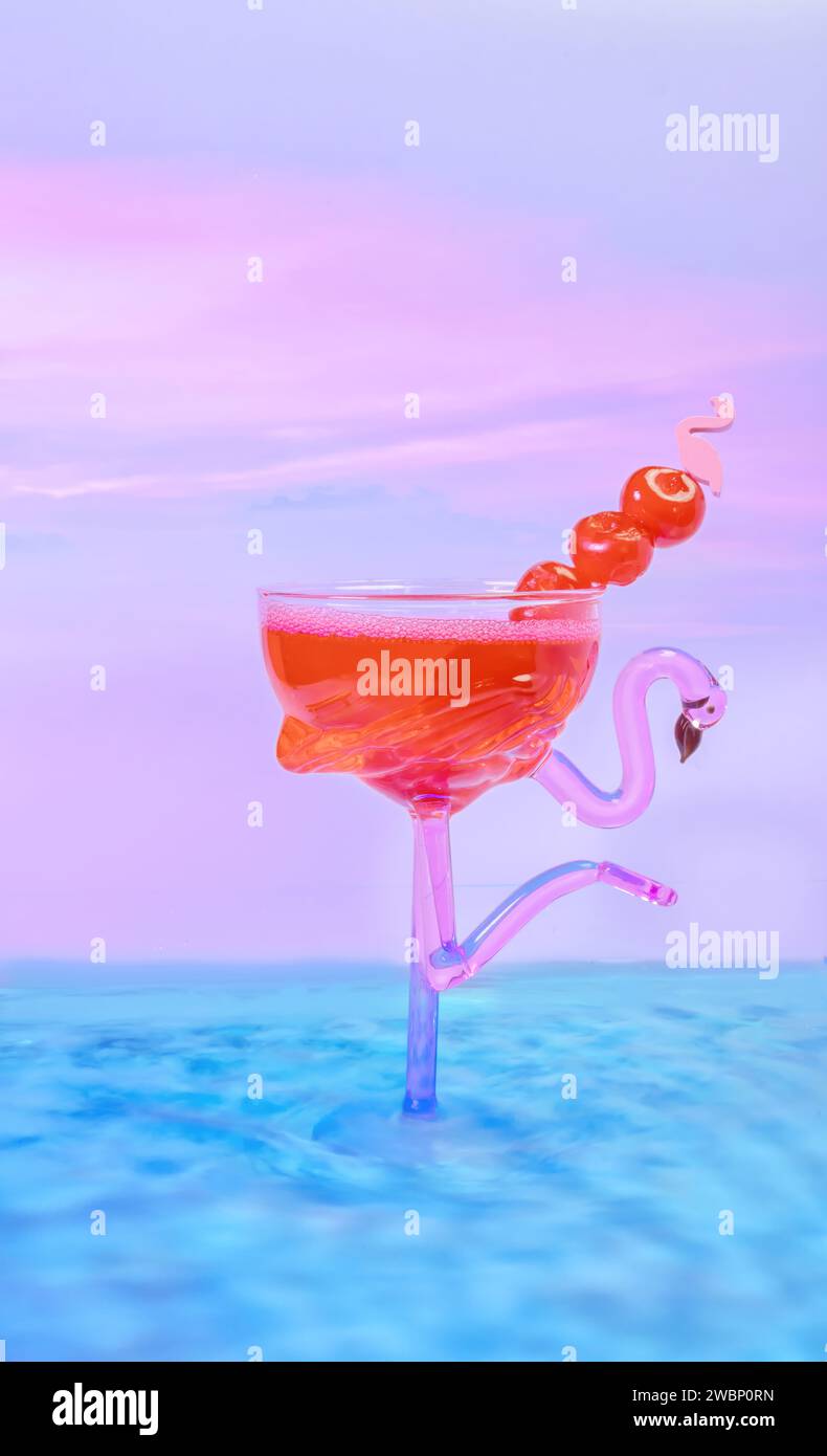 Ein wunderschönes Cocktail-Glas in rosa Flamingoform in blauem Wasser mit einem wunderschönen Candy-Sonnenuntergang aus Baumwolle im Hintergrund Stockfoto