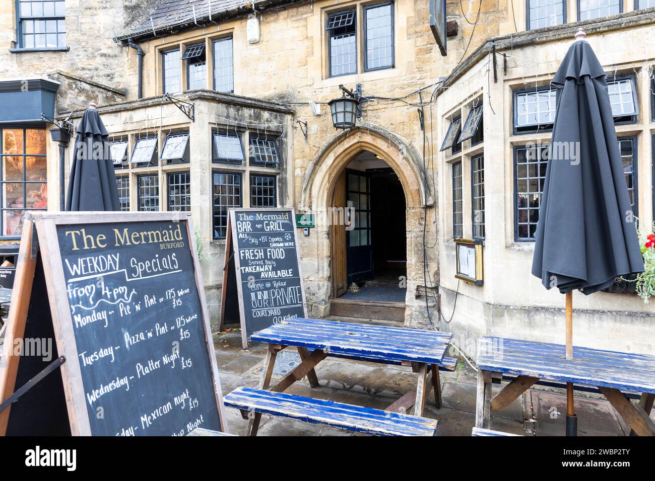 Burford Stadtzentrum in den Cotswolds, Oxfordshire und High Street Pub The Mermaid Inn, Außenansicht mit Menü, England, UK, 2023 Stockfoto