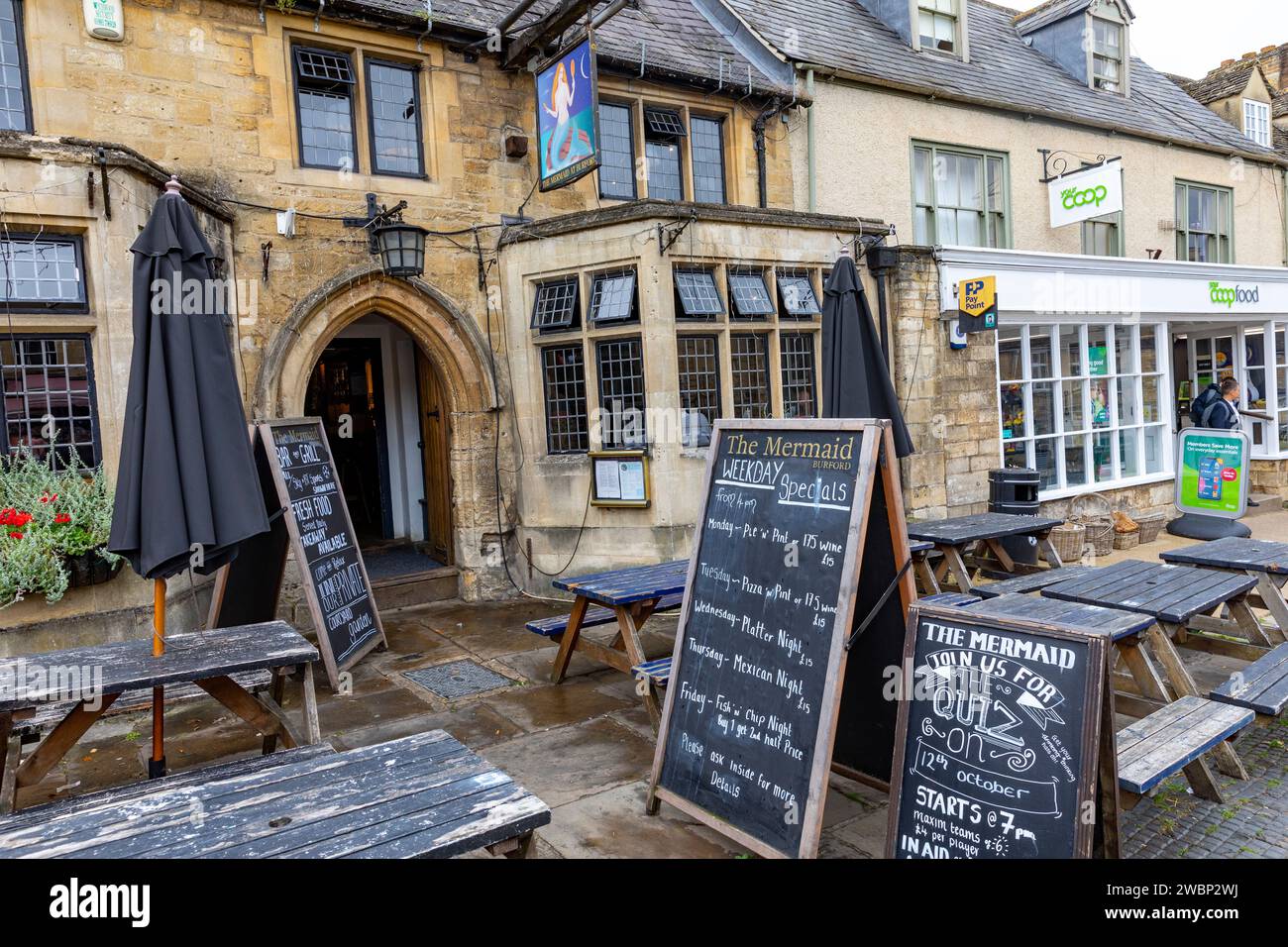 Burford Stadtzentrum in den Cotswolds, Oxfordshire und High Street Pub The Mermaid Inn, Außenansicht mit Menü, England, UK, 2023 Stockfoto