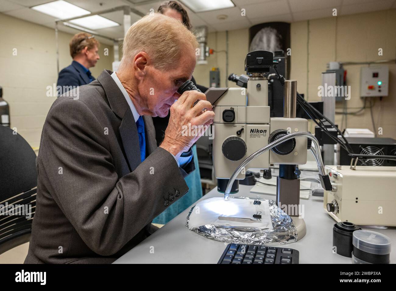 NASA-Administrator Bill Nelson verwendet ein Mikroskop, um eine Probe des Asteroiden Bennu am Freitag, den 3. November 2023, im Smithsonian’s National Museum of Natural History in Washington zu betrachten. Die Probe wurde im Oktober 2020 von der NASA-Raumsonde OSIRIS-REX aus dem kohlenstoffreichen Erdasteroiden Bennu entnommen. Stockfoto