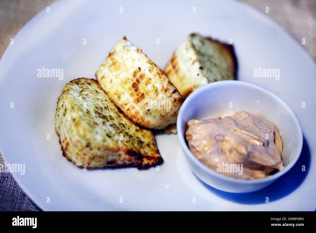 Köstlicher Adyghe-Käse liegt auf einer Untertasse mit Sauce Stockfoto