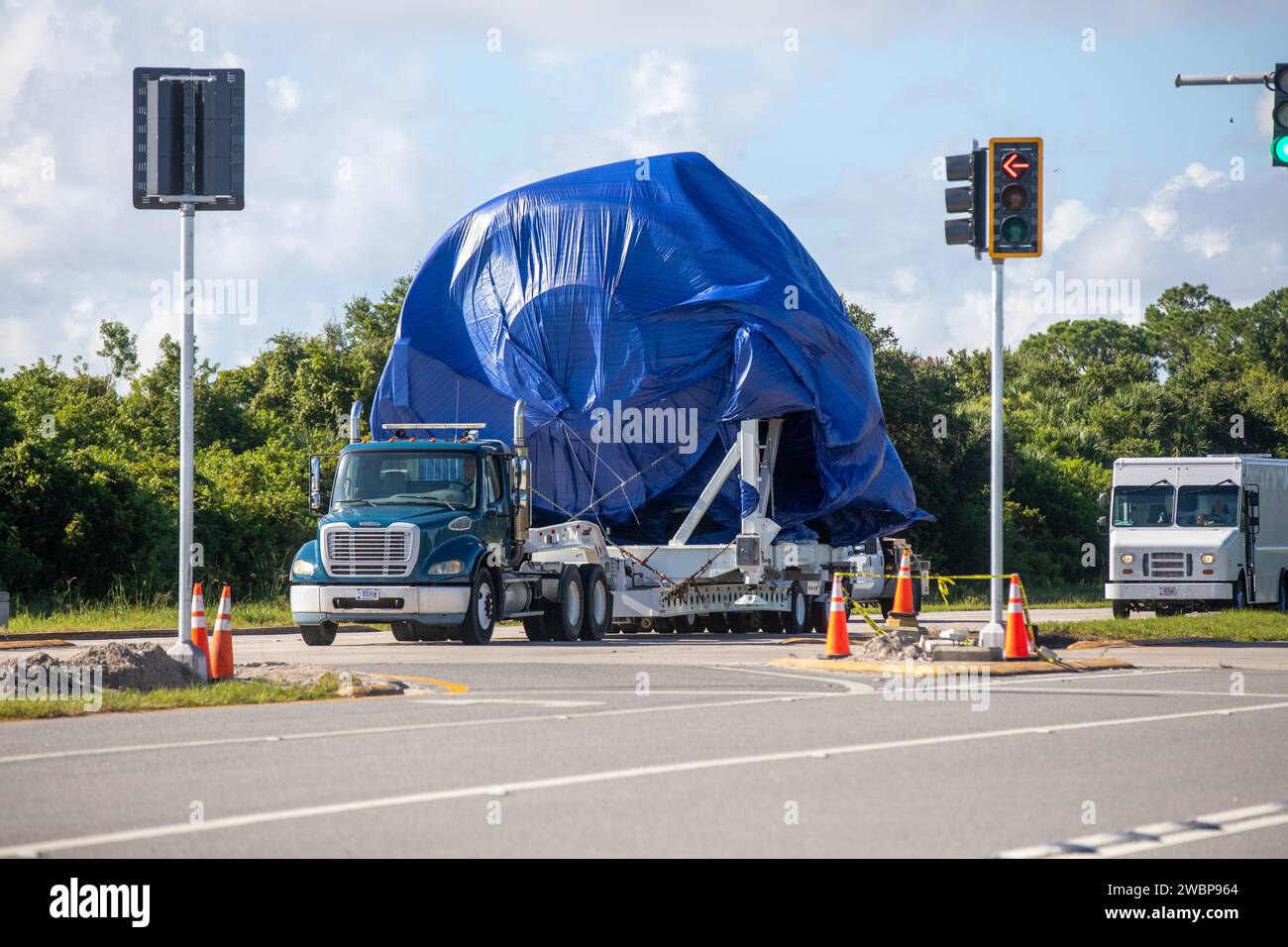 Am 20. Juli 2020 ist ein Tieflader mit dem Knotenaufbau-testartikel (STA) auf dem Weg zur Launch and Landing Facility von der Space Station Processing Facility (SSPF) im Kennedy Space Center der NASA in Florida. Im Blick ist das ikonische Montagegebäude. Der Node STA wurde verwendet, um zu beweisen, dass die Fertigungsprozesse und -Verfahren robust für ausgedehnte bemannte Raumflüge waren. Die gleichen Prozesse und Verfahren wurden dann zum Bau von Knoten 1 verwendet, den Kennedy Center Direktor Bob Cabana zur Raumstation STS 88 flog. Die NASA hat den Knoten STA im SSPF gespeichert, und er wird nach verschoben Stockfoto