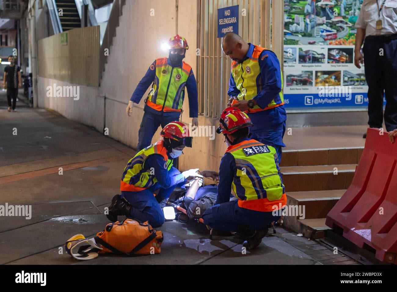 Kuala Lumpur, Malaysia - 6. Januar 2024: Sanitäter werden gesehen, wie sie einem nicht identifizierten Mann erste Hilfe auf der Straße in Kuala Lumpur, Malaysia, leisten. Stockfoto