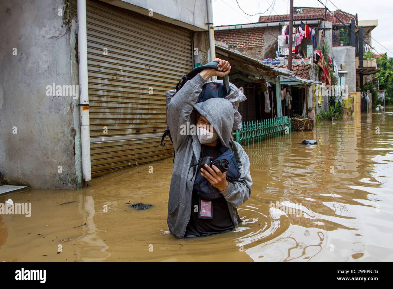 Bandung, West-Java, Indonesien. Januar 2024. Ein Journalist durchquert die Flut in Dayeuhkolot. Der Überlauf des Citarum River aufgrund der hohen Regenintensität am Donnerstag, 11. Januar 2024 nachmittags bis abends führte dazu, dass Hunderte von Häusern in vier Unterbezirken der Bandung Regency in Hochwasserlagen von 50 Zentimetern bis zwei Metern getaucht waren. (Kreditbild: © Algi Febri Sugita/ZUMA Press Wire) NUR REDAKTIONELLE VERWENDUNG! Nicht für kommerzielle ZWECKE! Stockfoto