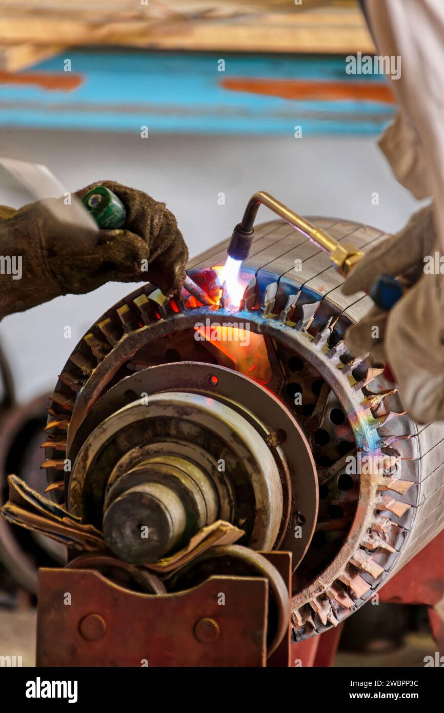 Elektromotor umwickeln, alte Wicklung mit einem Brenner durchtrennen Stockfoto