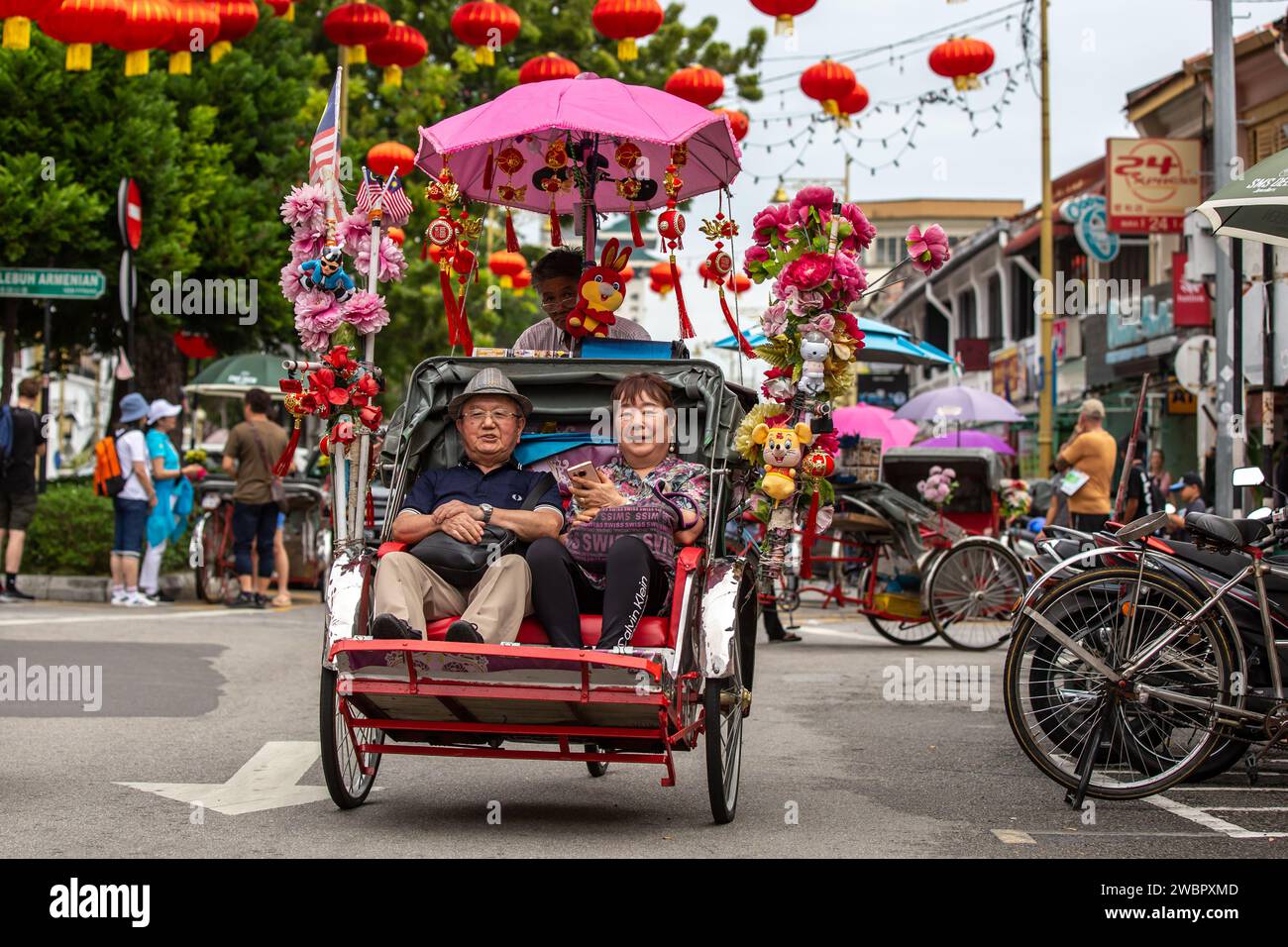 George Town, Penang, Malaysia – 9. Januar 2024: Unbekannte Menschen, die mit einer Trischa durch die Straßen von George Town, Penang, Malaysia fahren. Stockfoto