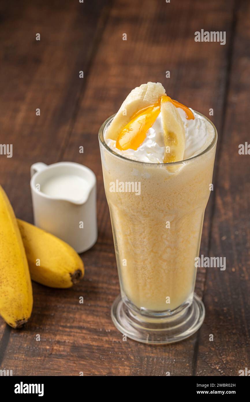 Bananen-Smoothie in Glasbecher auf Holztisch Stockfoto