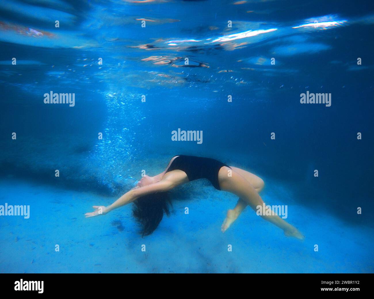Weibliche künstlerische Schwimmen unter Wasser im Meer Stockfoto