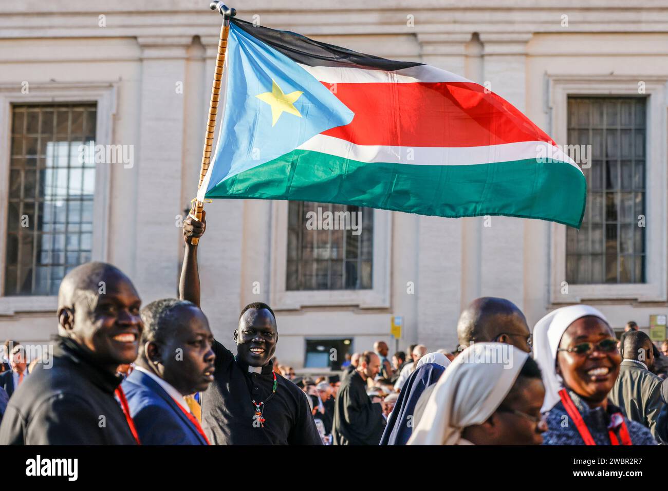 Ein Priester, der eine südsudanesische Flagge schwenkt, wartet auf den Beginn eines Konsistoriums in St. Peter-Platz im Vatikan, 30. September 2023. Stockfoto